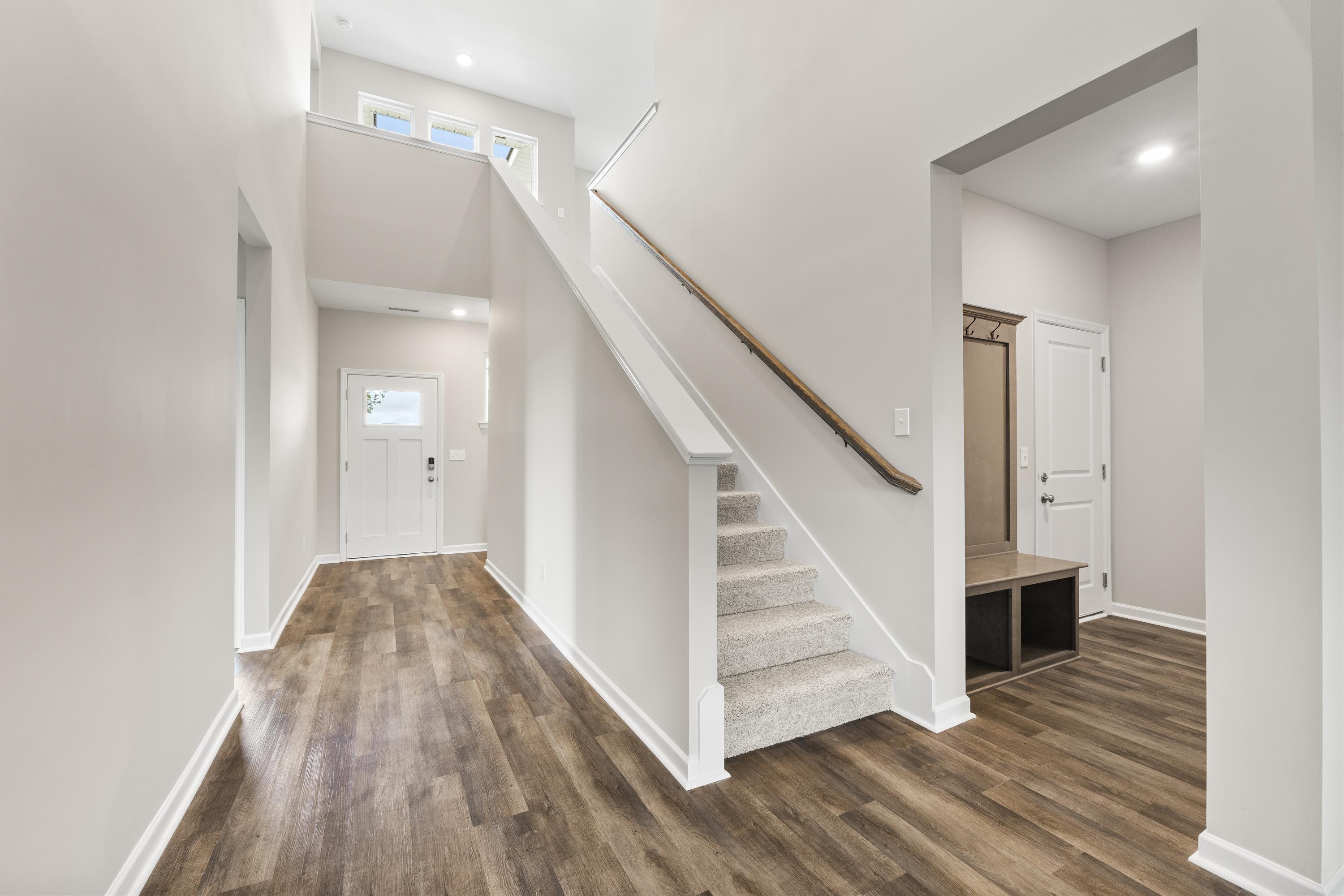 Grand entry foyer of The Haven E with open wooden staircase, light oak hardwood floors, and neutral white walls