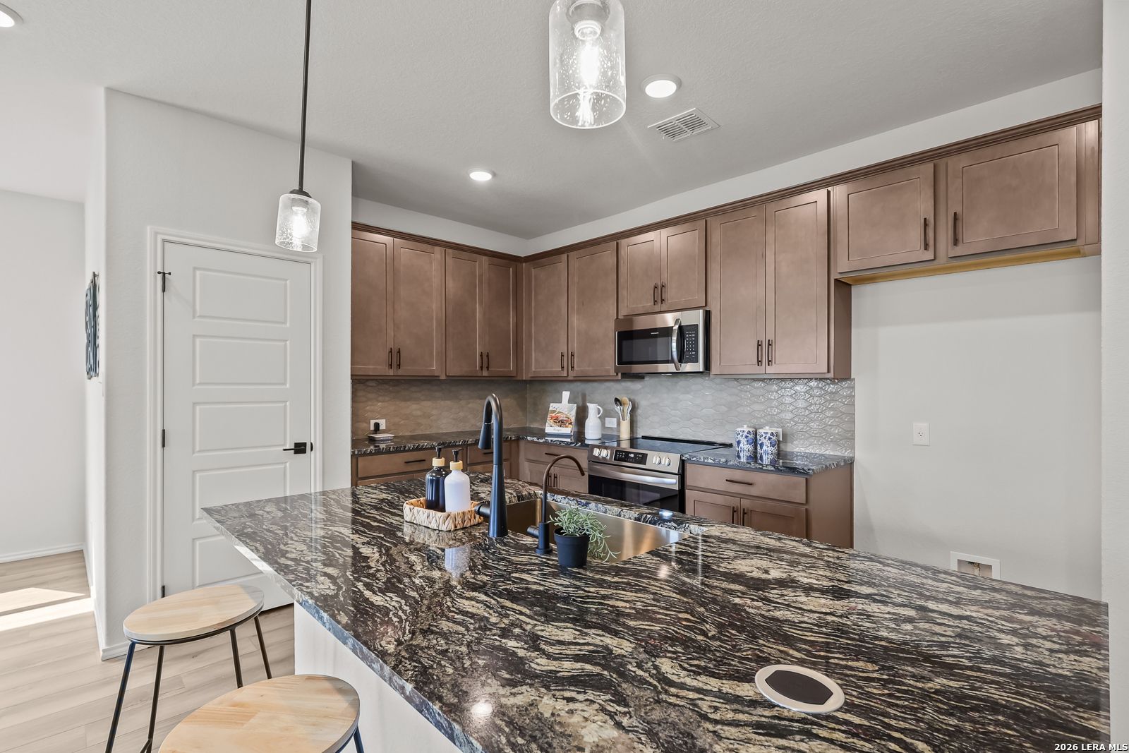 Modern kitchen featuring granite island, shaker cabinets, stainless appliances in The Daphne H 3-bedroom home, Seguin, Texas