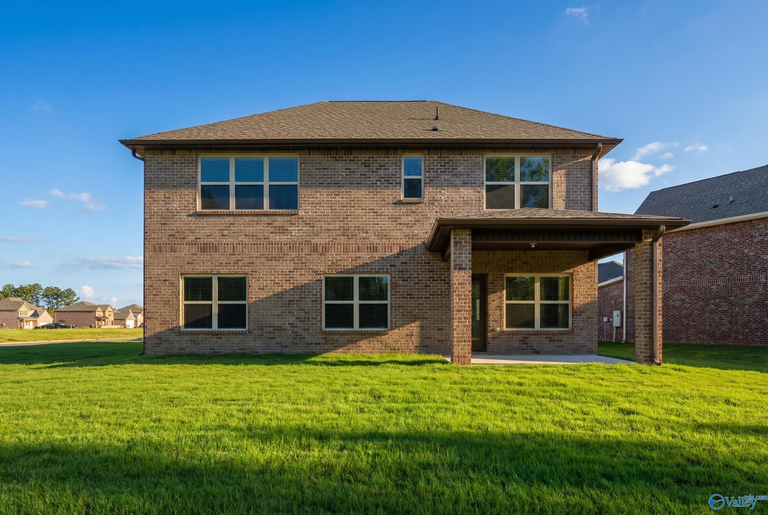 Two-story brick home with covered front porch, garage, and green lawn in Ricketts Farm, Athens, Alabama - Davidson Homes Shelby A