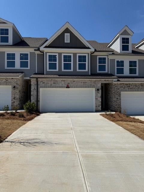 Modern 2-story townhome exterior with gray siding, stone accents, 2-car garage, and driveway in Hemingway, Cumming, Georgia