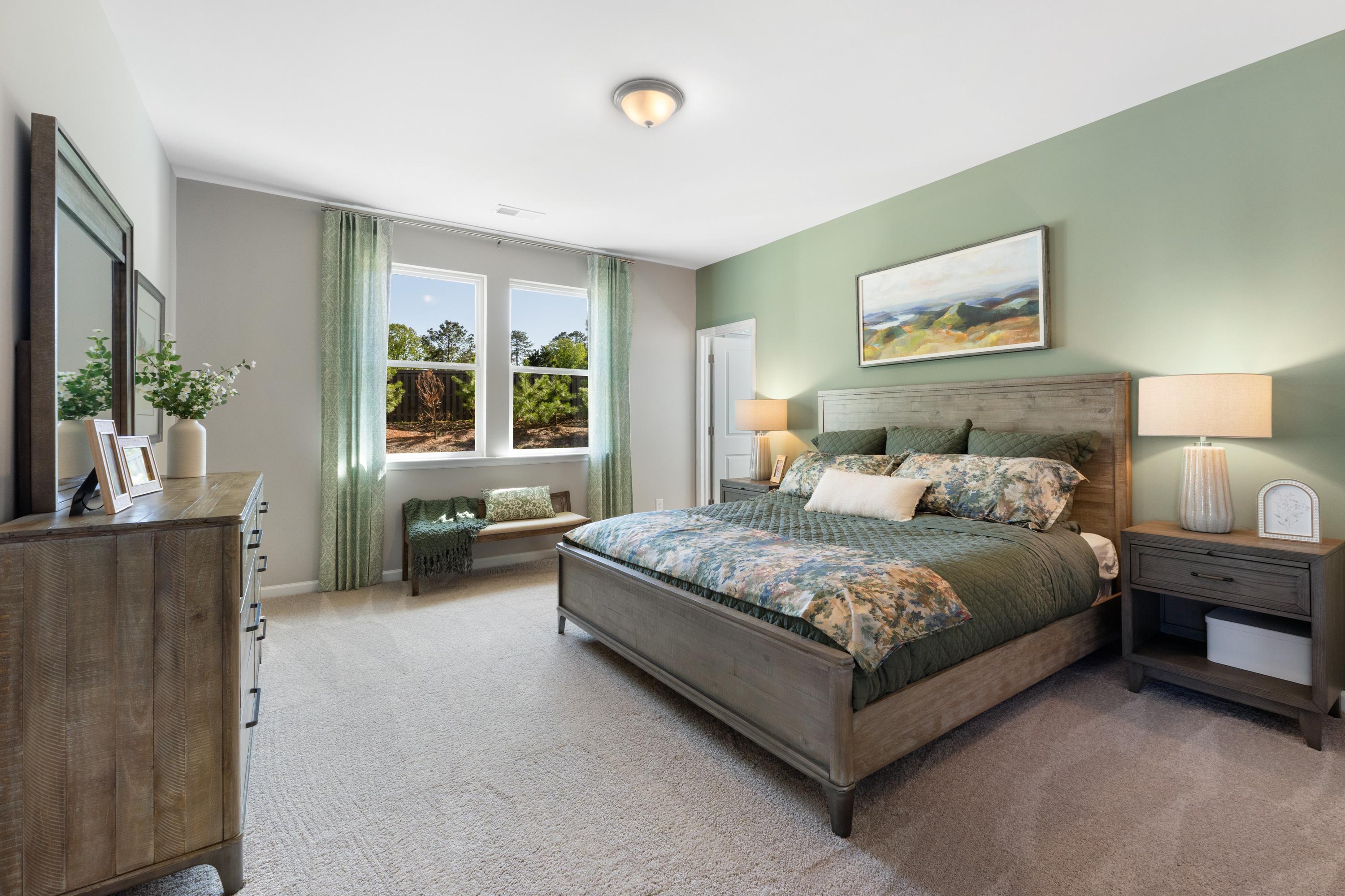 Spacious master bedroom at Evergreen Mill in Madison AL with sage green walls, king bed, floral bedding, and large windows