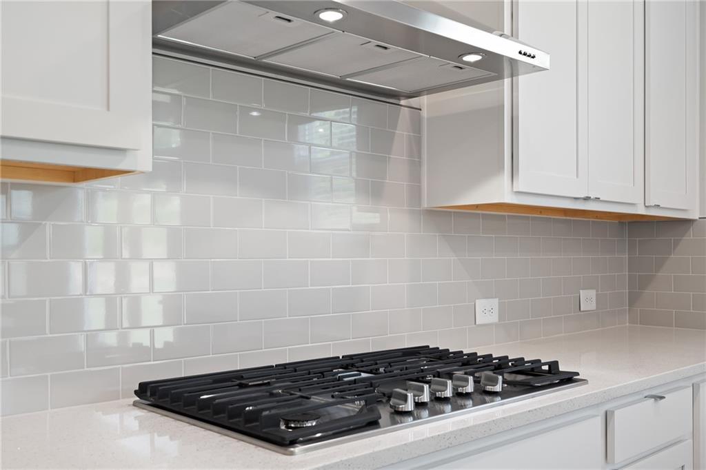 Modern white kitchen with gas cooktop, quartz countertop, subway tile backsplash in The Hickory A by Davidson Homes, Winder, GA