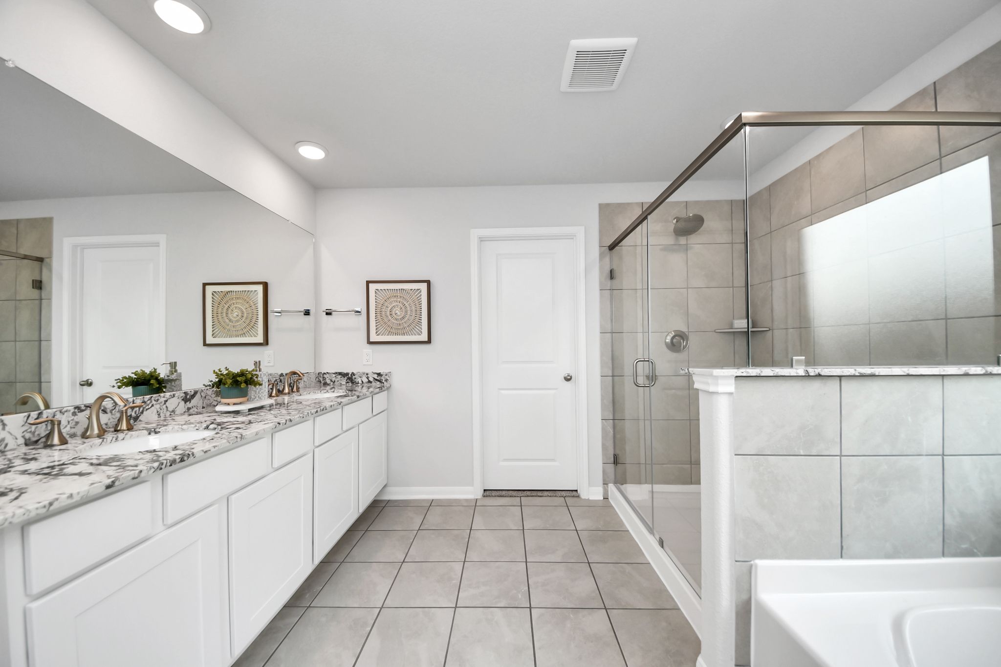 Modern primary bathroom at Sunterra in Katy, TX by Davidson Homes featuring granite countertops and walk-in glass shower.