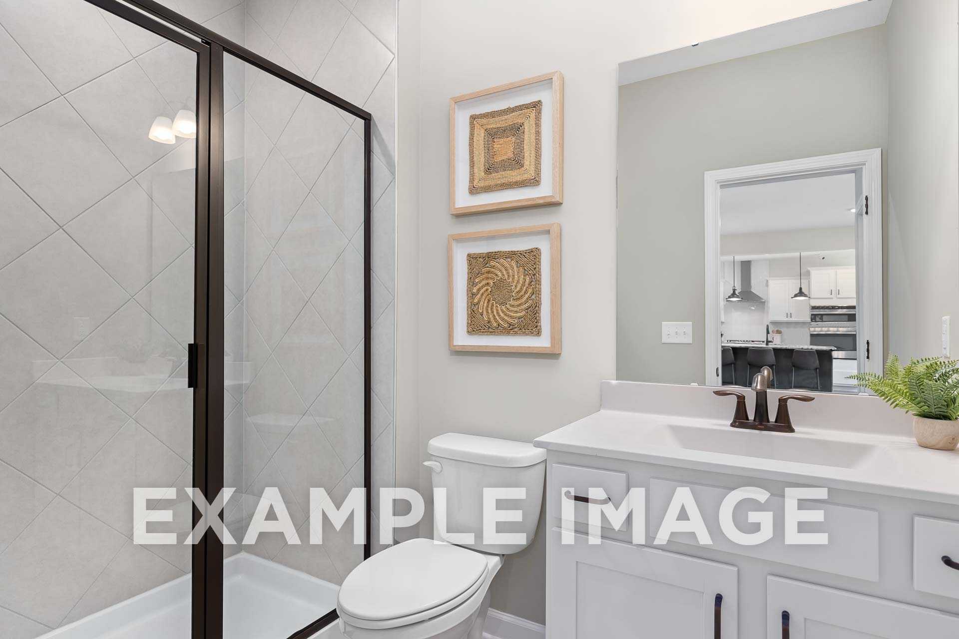 Modern master bathroom in The Willow F by Davidson Homes, featuring glass shower, subway tile walls, double vanity, and woven art accents