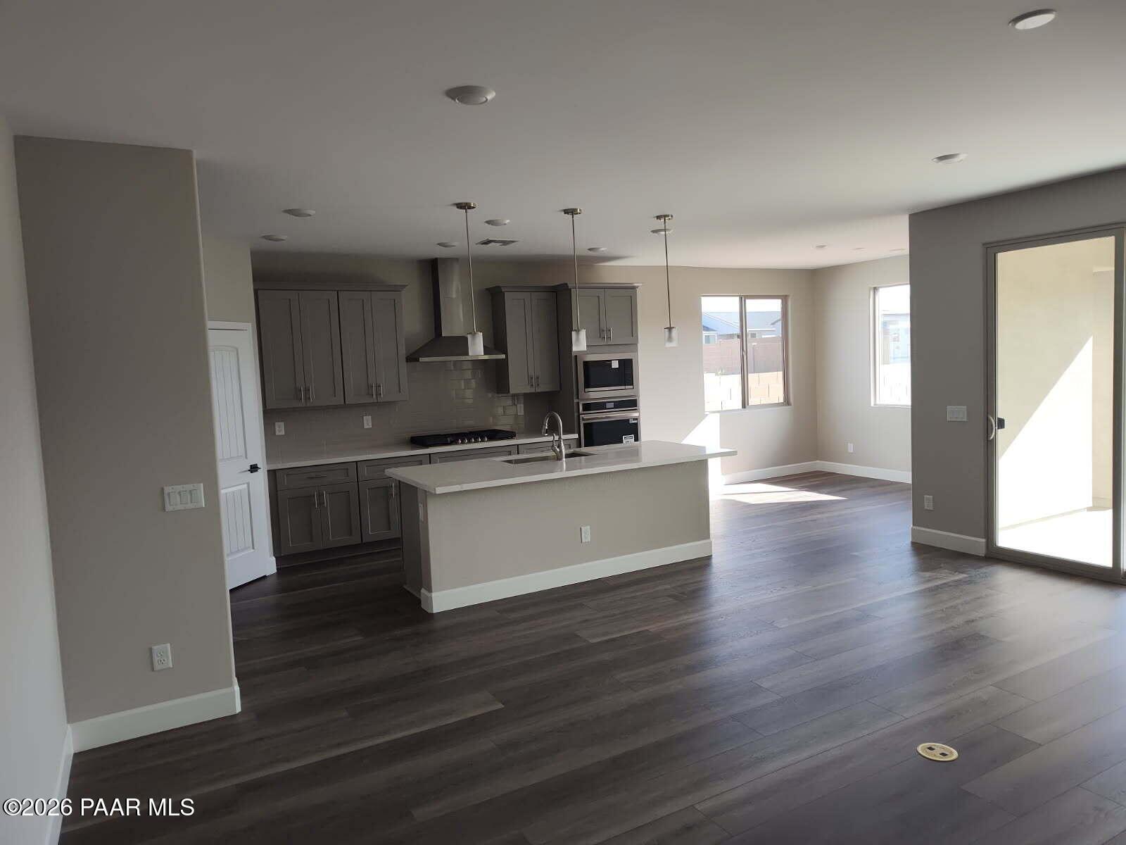 Modern open-concept kitchen with gray shaker cabinets, quartz island, stainless appliances, and sliding doors in Davidson Homes The Harmony C, Prescott Valley, AZ
