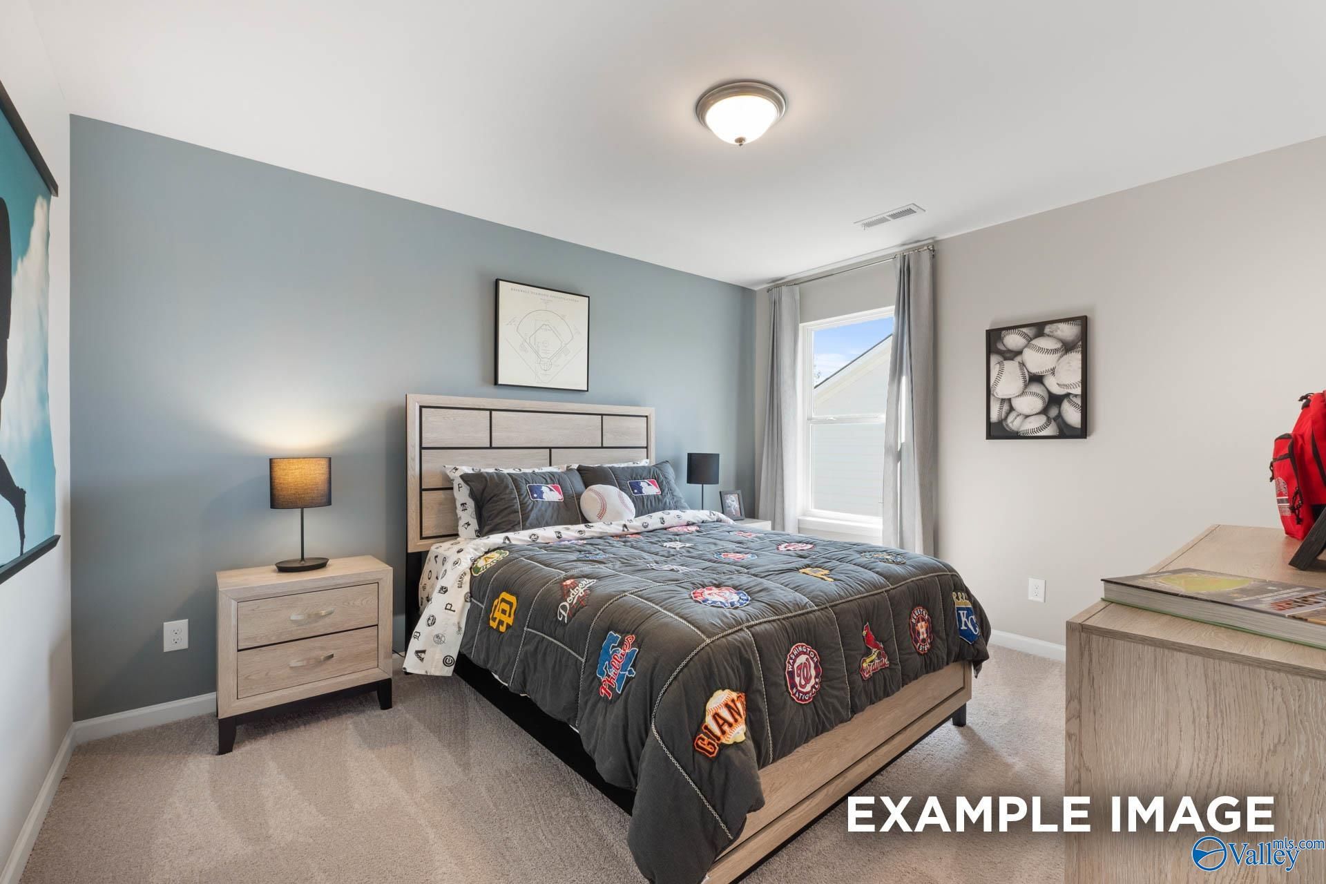 Cozy children's bedroom with superhero comforter on full bed, nightstands, lamp, and window in Davidson Homes The Stella, Madison AL