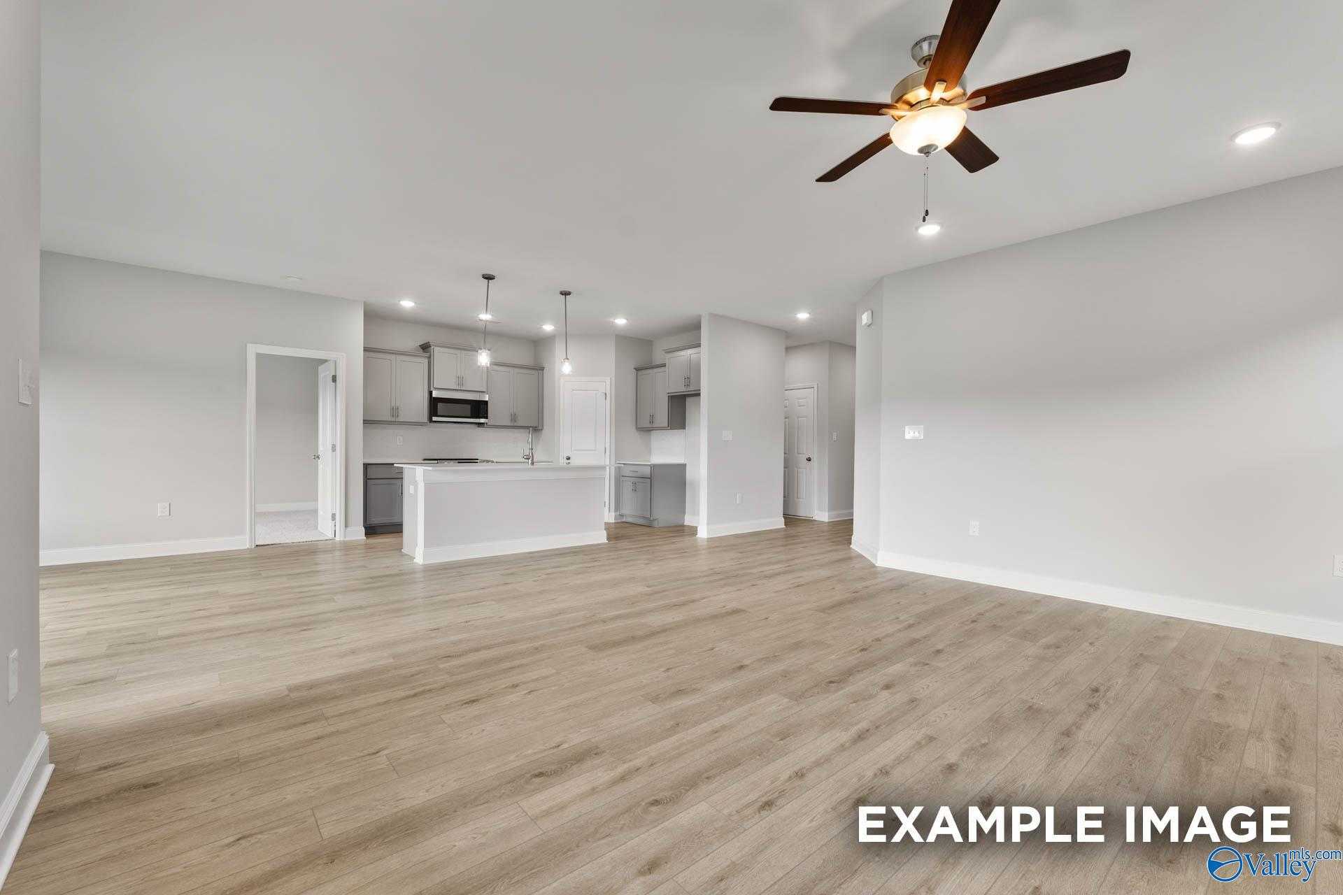 Modern open kitchen with white cabinets, stainless appliances, island, and ceiling fan in Davidson Homes The Franklin C, Athens Alabama