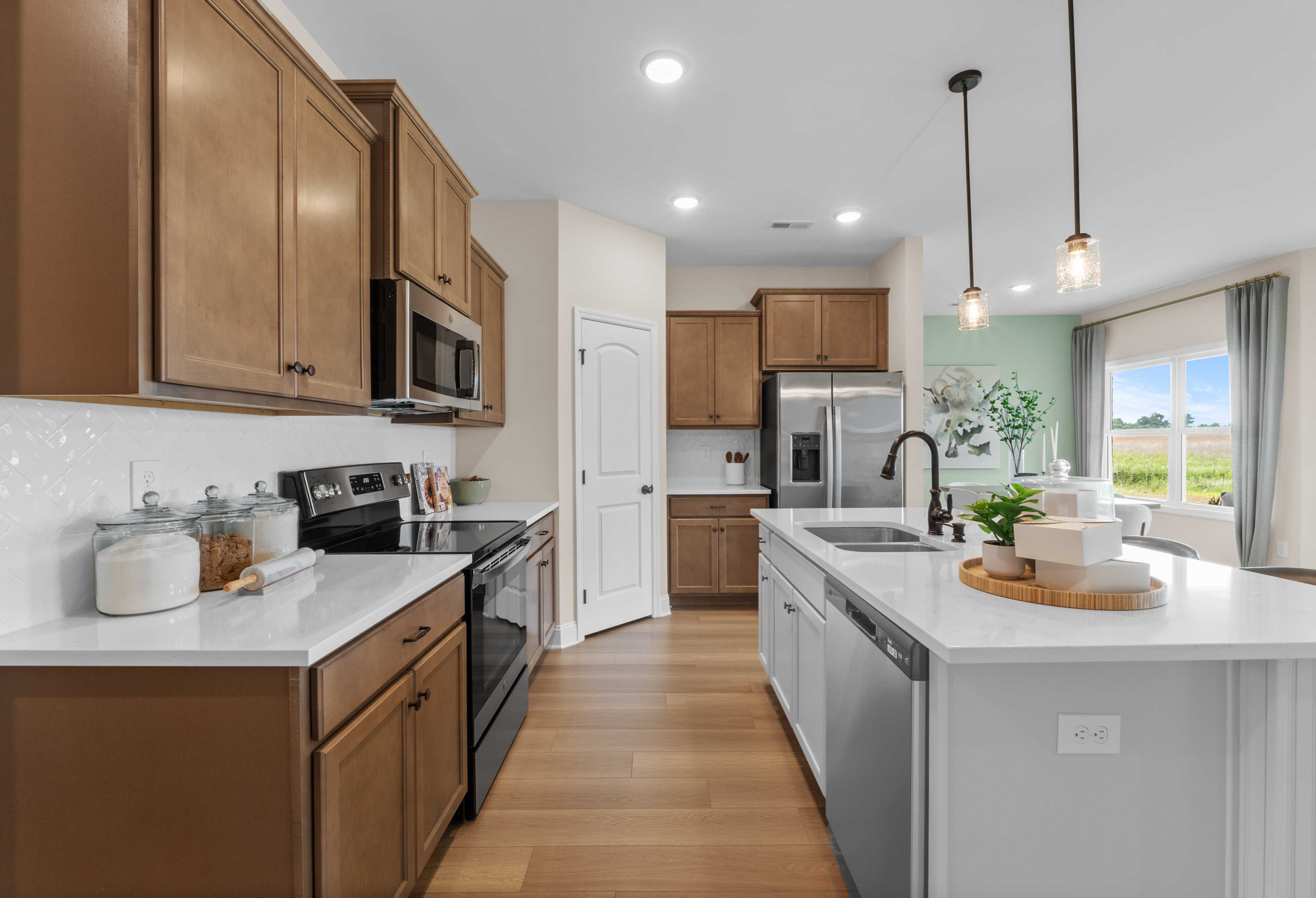 Modern kitchen in The Daphne floor plan with shaker cabinets, white quartz island, stainless steel appliances, and field view