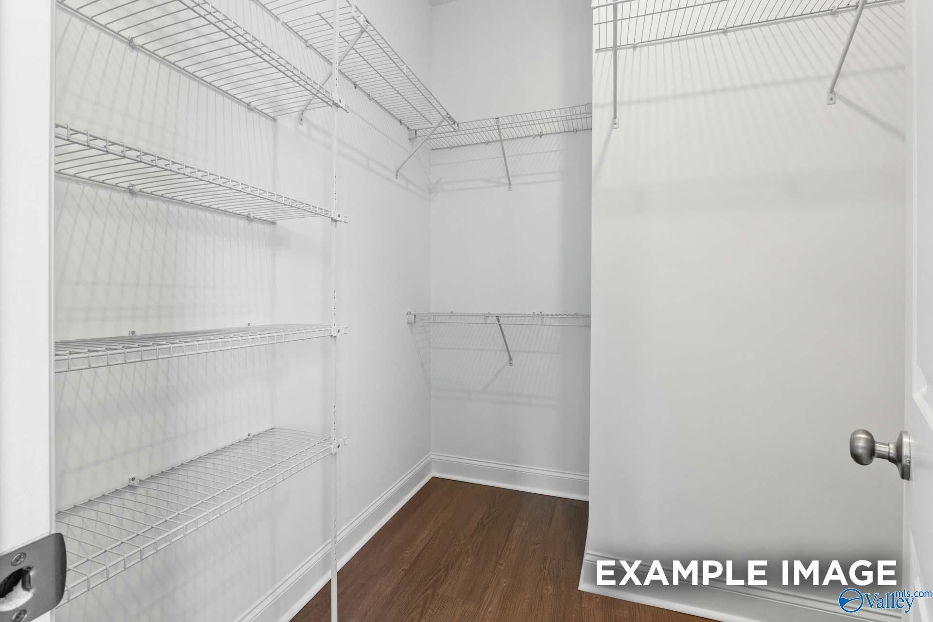 Spacious walk-in closet with white wire shelving and hardwood floors in Evermore Homes The Haven E, Owens Cross Roads, Alabama