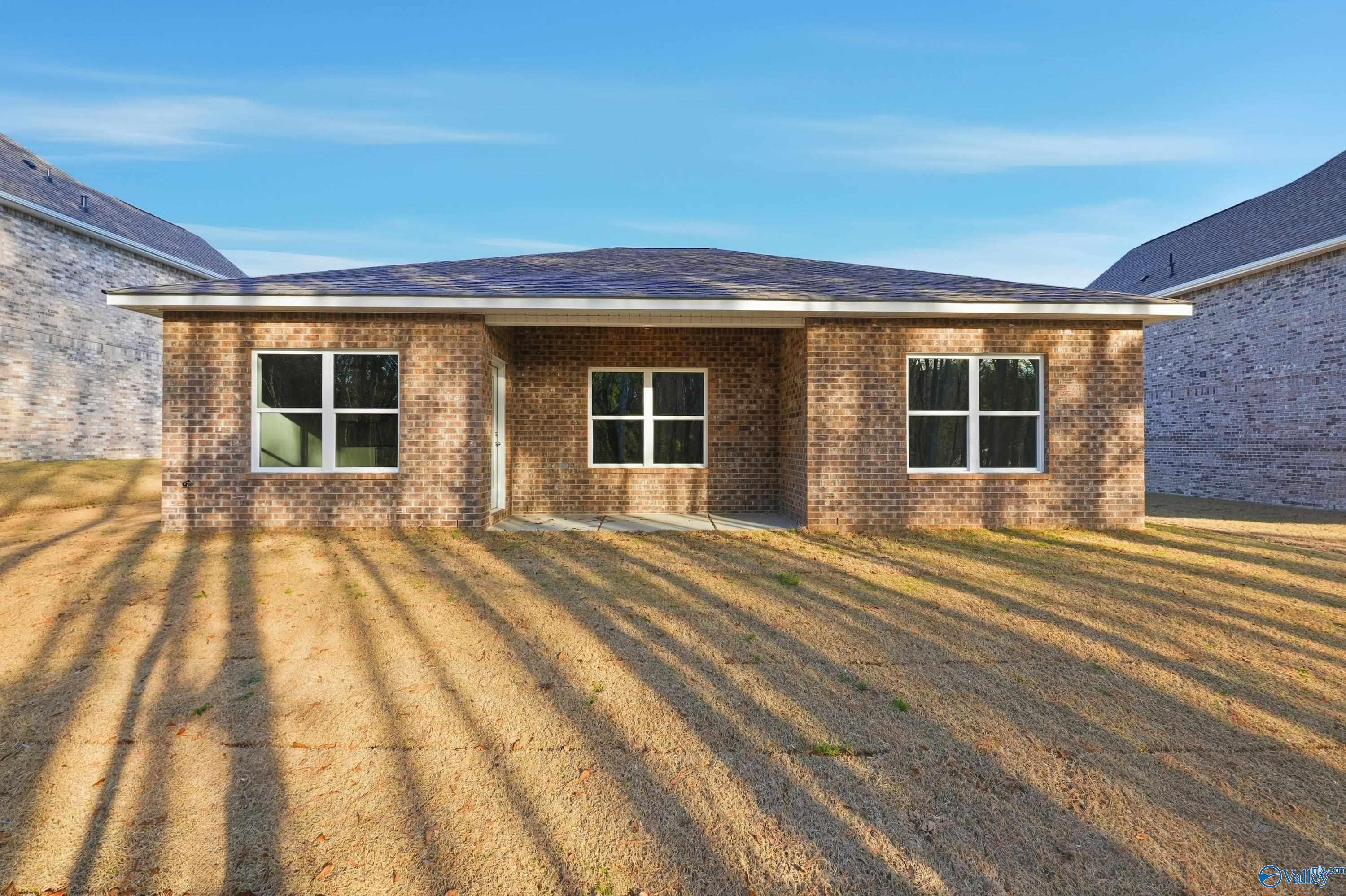 Single-story brick home exterior with dark shingled roof, three front windows, and covered entry in The Highlands, Arab, Alabama by Davidson Homes