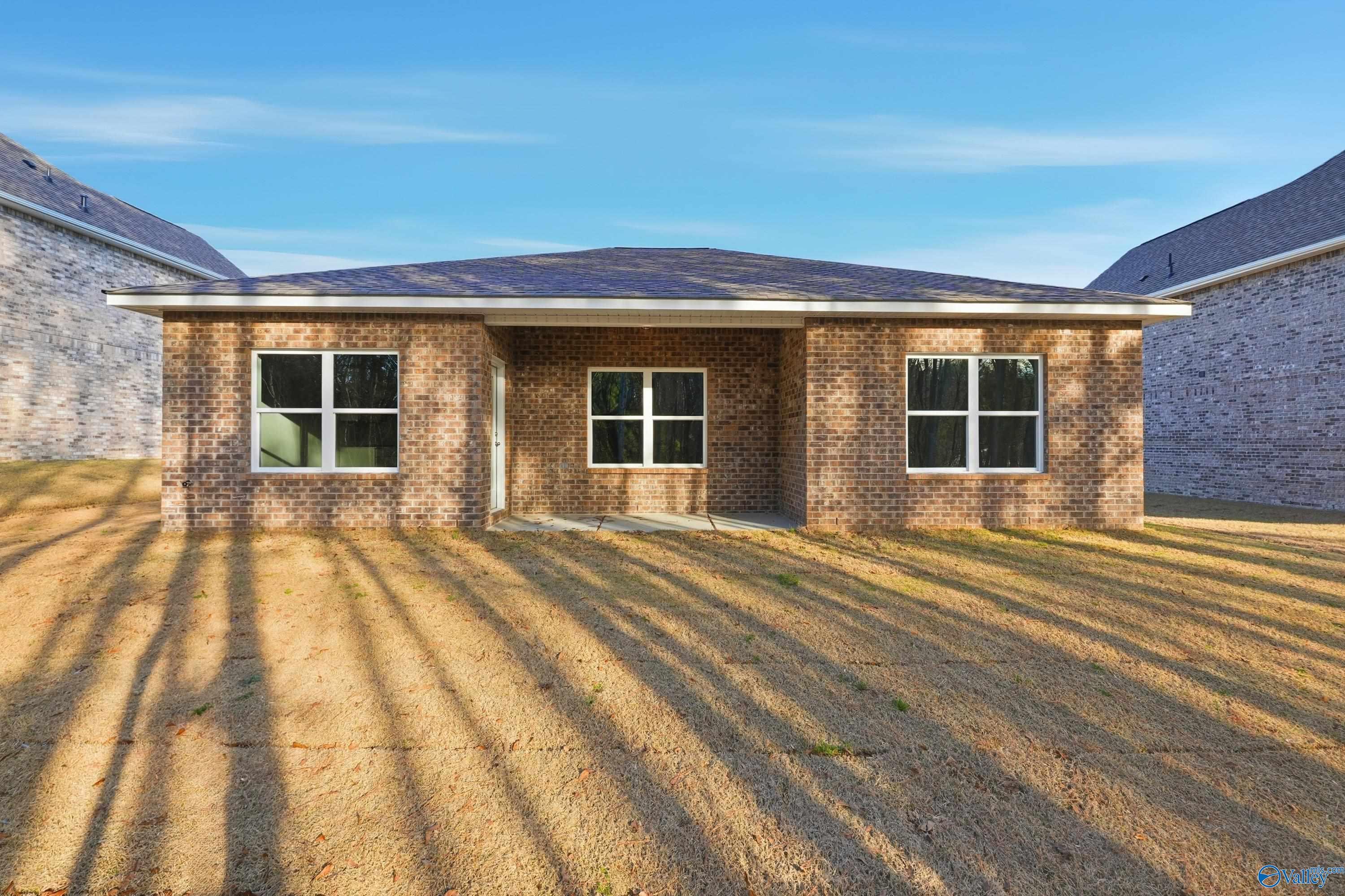 Single-story brick home exterior with dark shingled roof, three front windows, and covered entry in The Highlands, Arab, Alabama by Davidson Homes