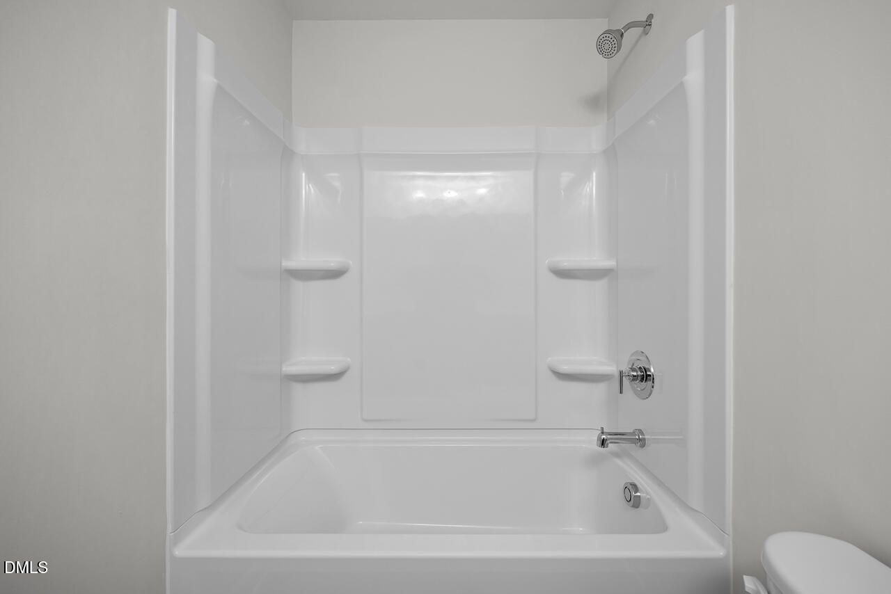 White fiberglass tub-shower combination with built-in shelves in The Grace C floor plan at Retreat at North Main.