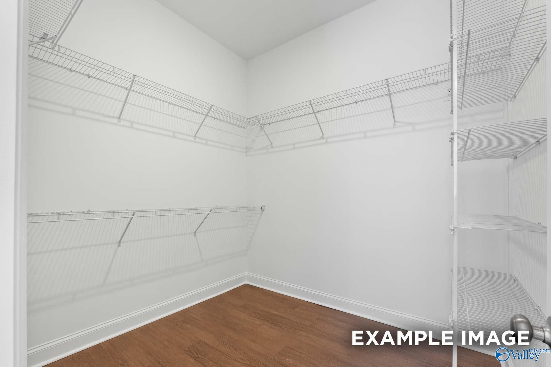 Spacious walk-in closet with white wire shelving and hardwood floors in 5-bedroom The Haven E home, Owens Cross Roads, Alabama