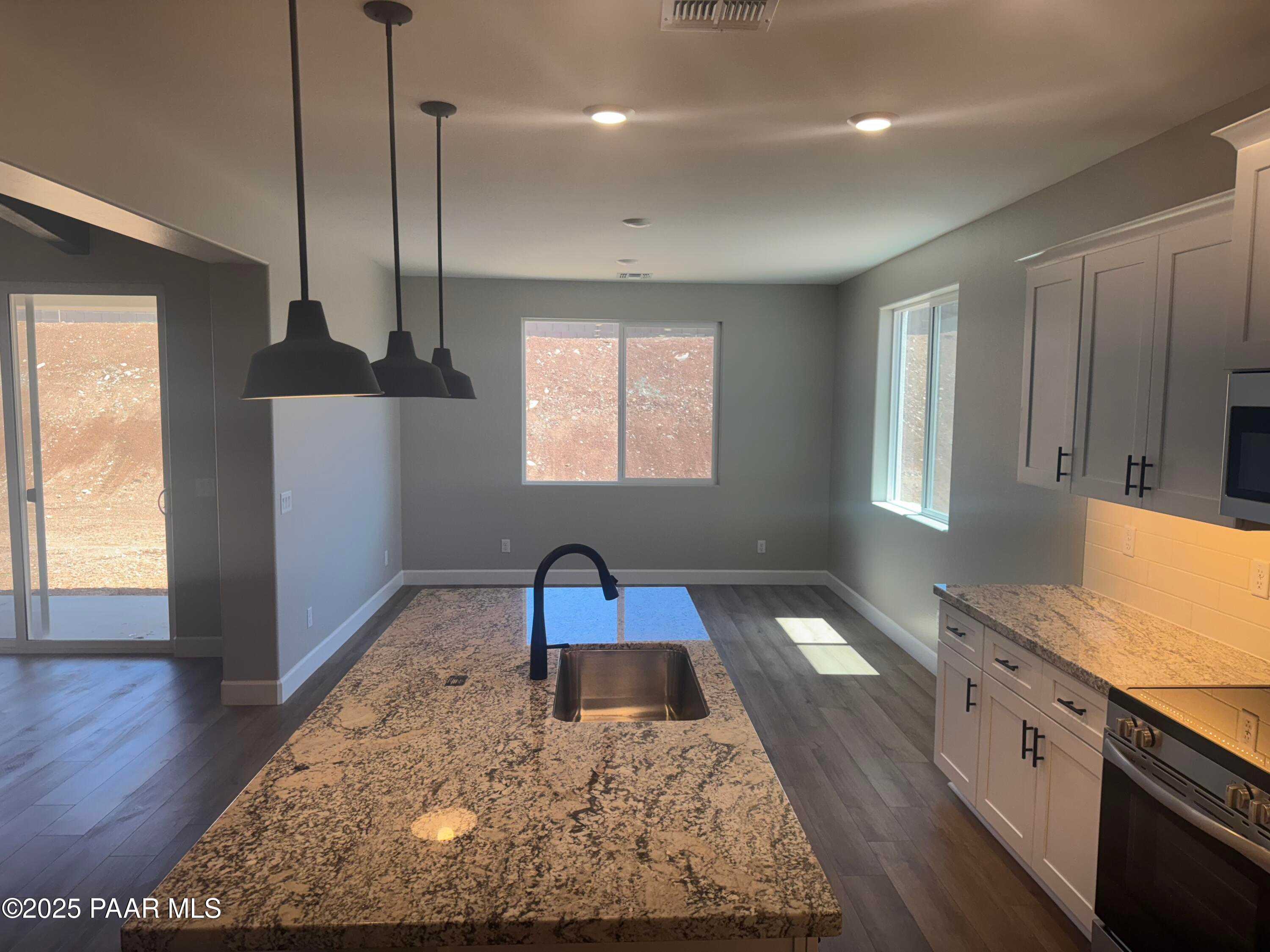 Modern kitchen featuring granite island, stainless appliances, white cabinets in Evermore Homes The Summit B, Prescott Valley, AZ