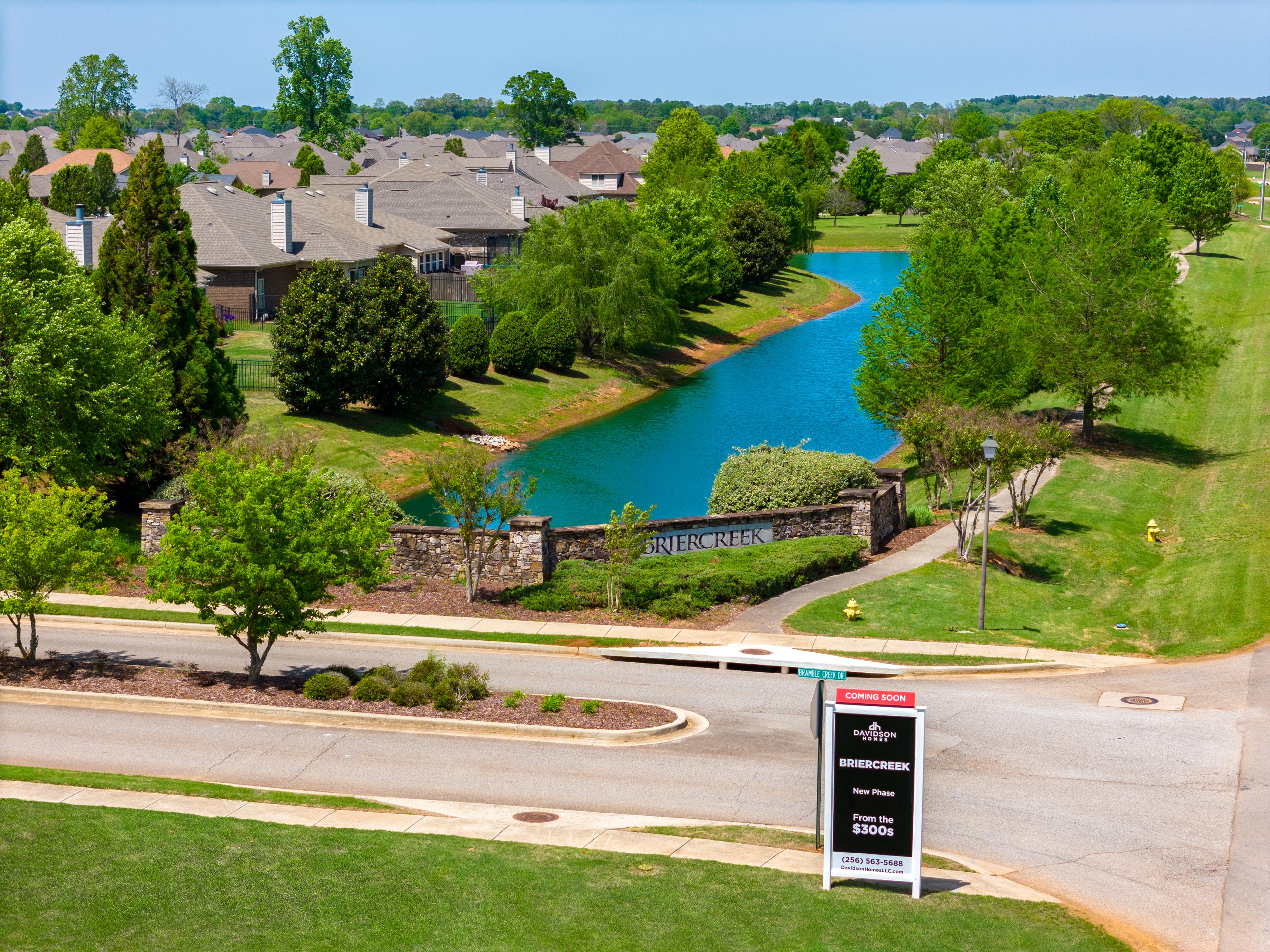 Briercreek neighborhood entrance in Meridianville Alabama with serene pond, lush trees, stone gateway, and Davidson Homes sign