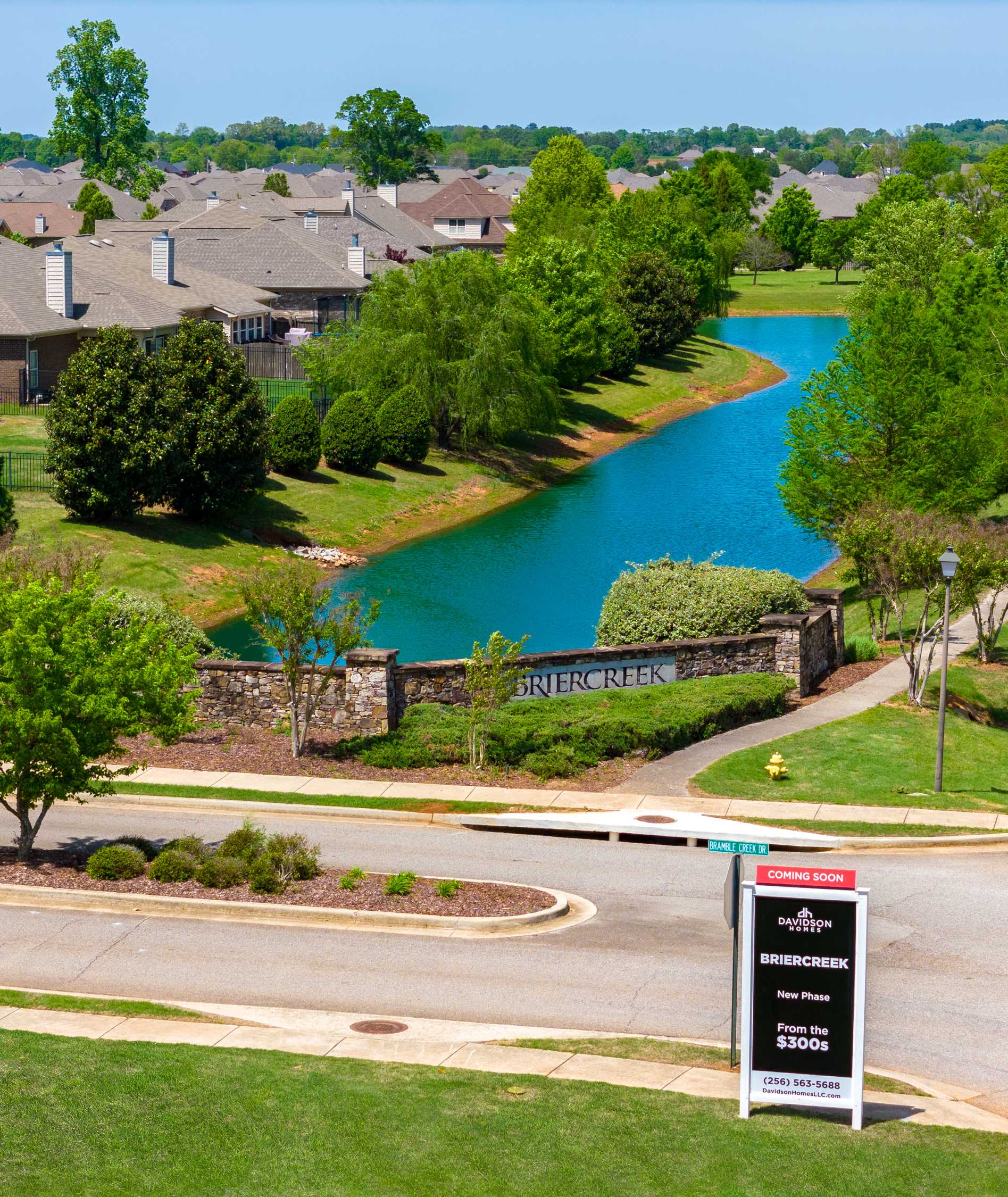Briercreek neighborhood entrance in Meridianville Alabama with serene pond, lush trees, stone gateway, and Davidson Homes sign