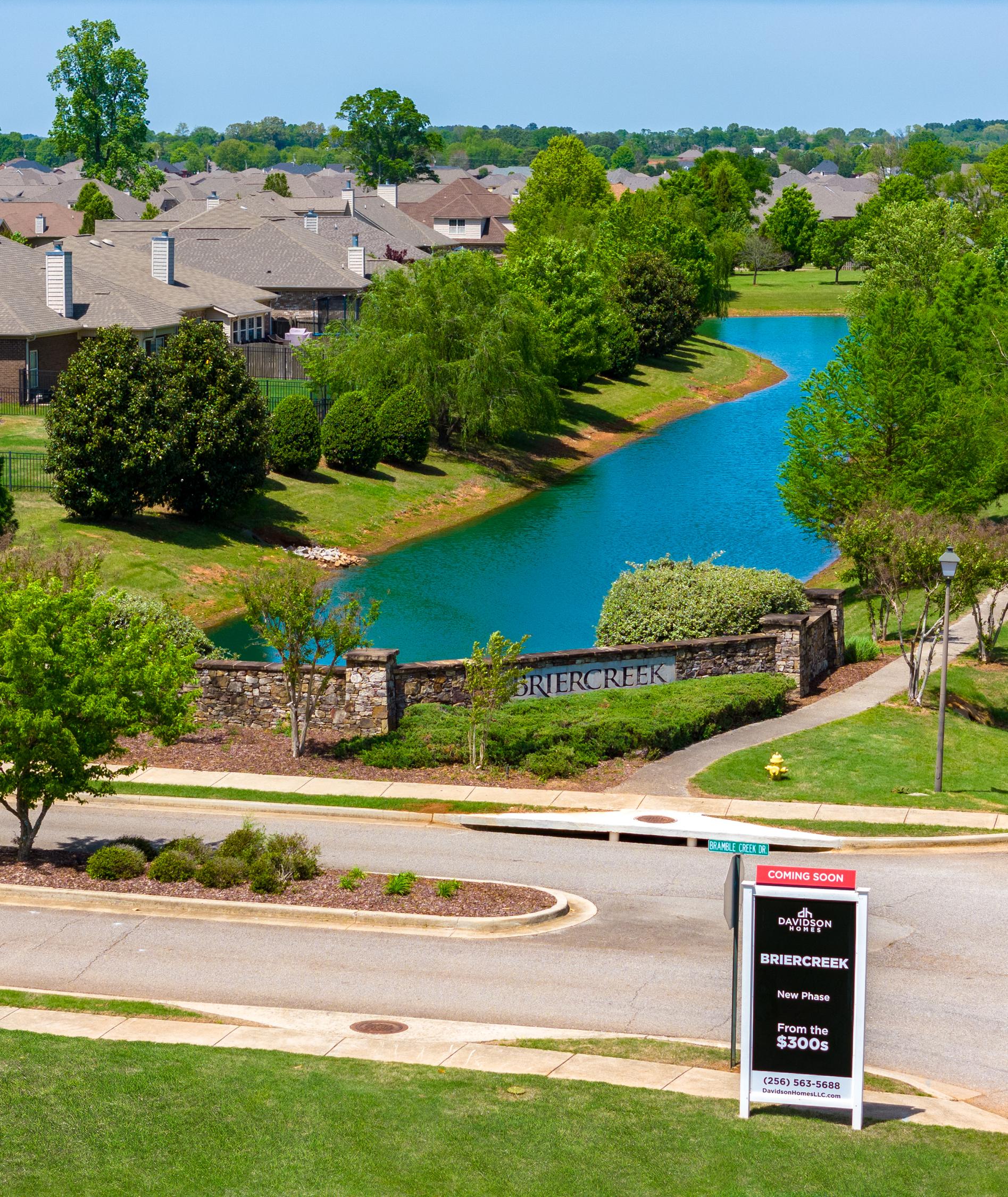 Briercreek neighborhood entrance in Meridianville Alabama with serene pond, lush trees, stone gateway, and Davidson Homes sign