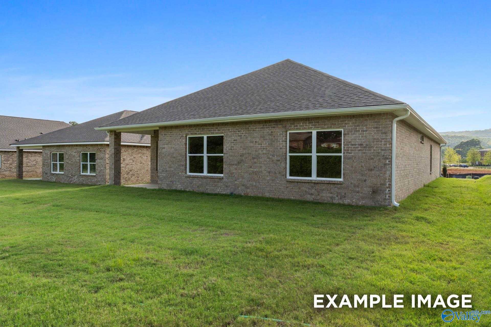 Single-story brick home with gabled roof, double windows, and attached garage on lush green lawn in Creek Grove, New Market, Alabama