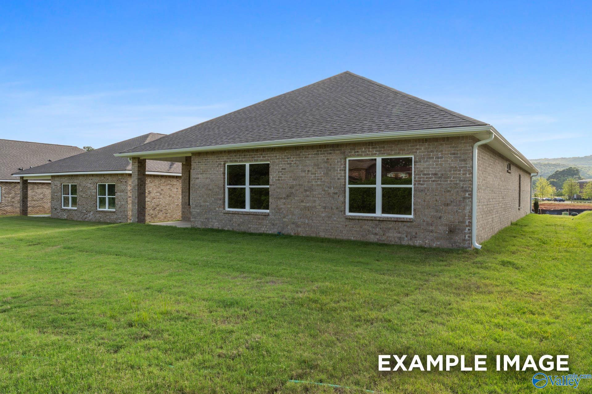 Single-story brick home with gabled roof, large windows, 2-car garage, and lush green lawn in Ivy Hills, Toney, Alabama