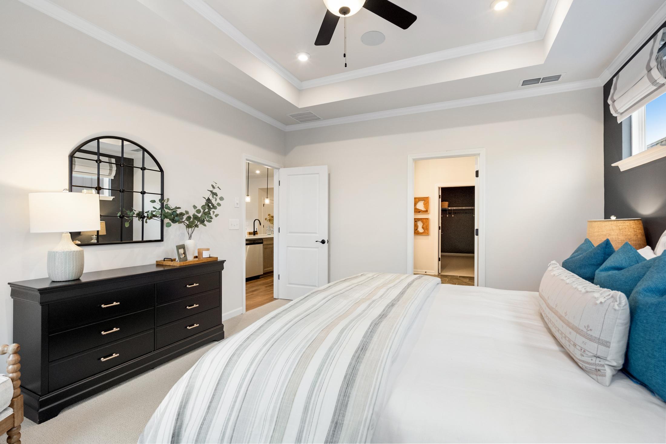 Spacious master bedroom at Kelly Preserve in Loganville GA with king bed, black dresser, arched mirror and en-suite bath