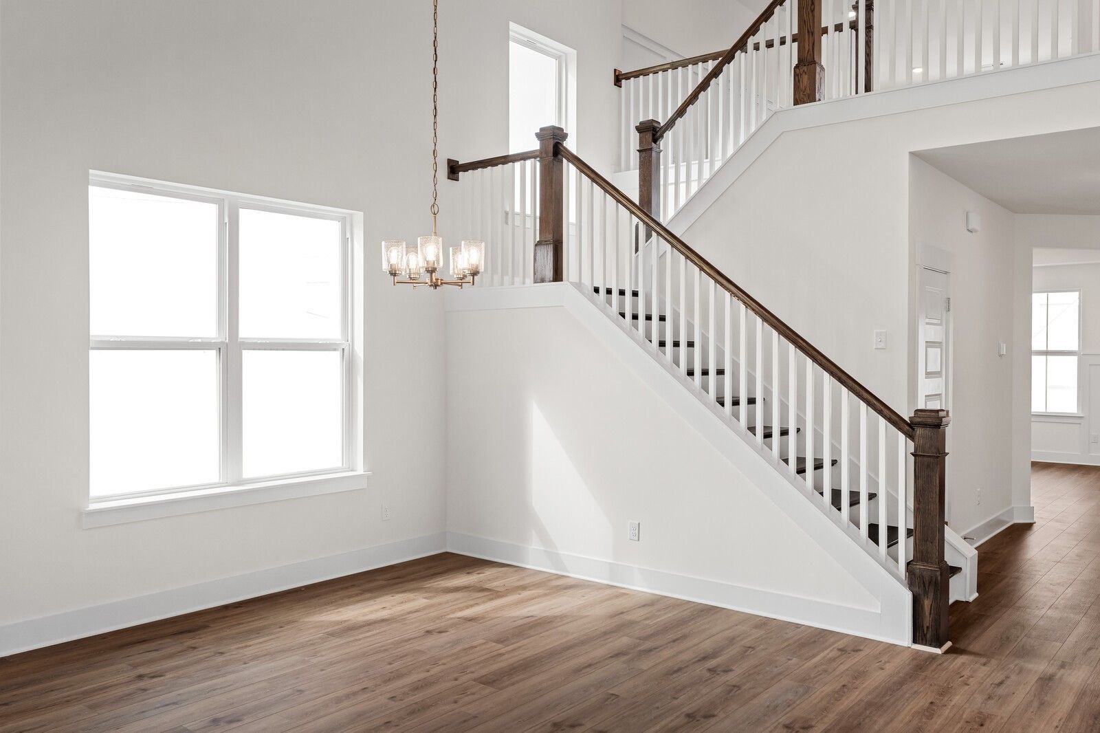 Grand wooden staircase with chandelier in open two-story foyer, hardwood floors, large windows in The Ridgeport home, Gallatin, TN