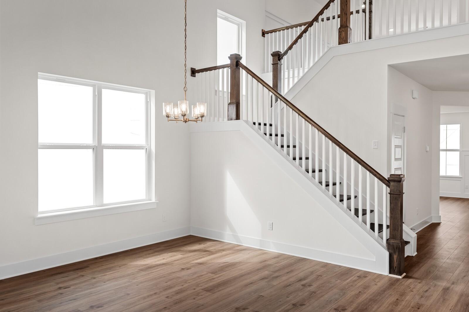 Grand wooden staircase with chandelier in open two-story foyer, hardwood floors, large windows in The Ridgeport home, Gallatin, TN