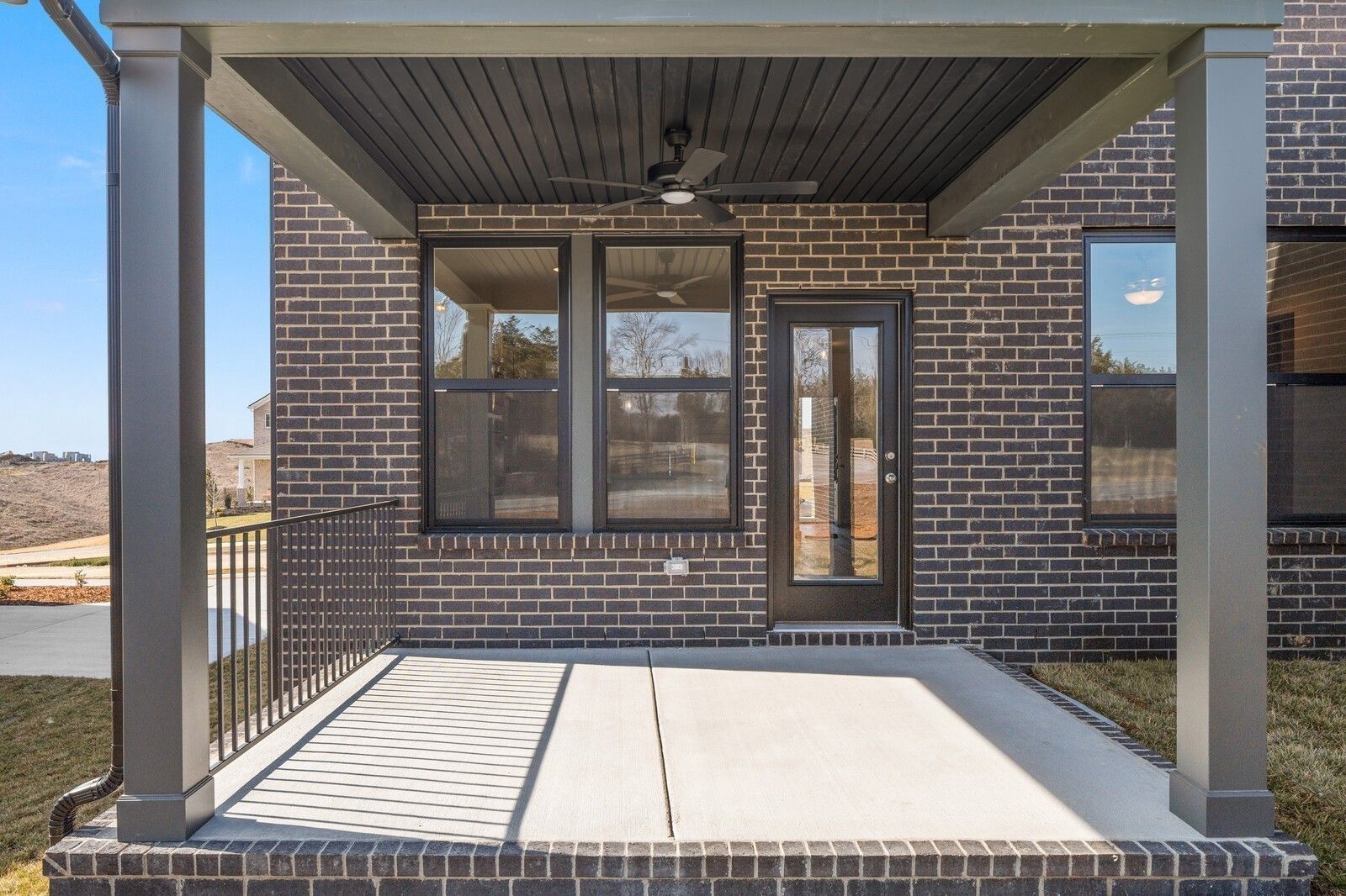 Covered back patio with dark brick exterior and ceiling fan at The Willow D home in Benders Cove, Mt. Juliet, Tennessee.