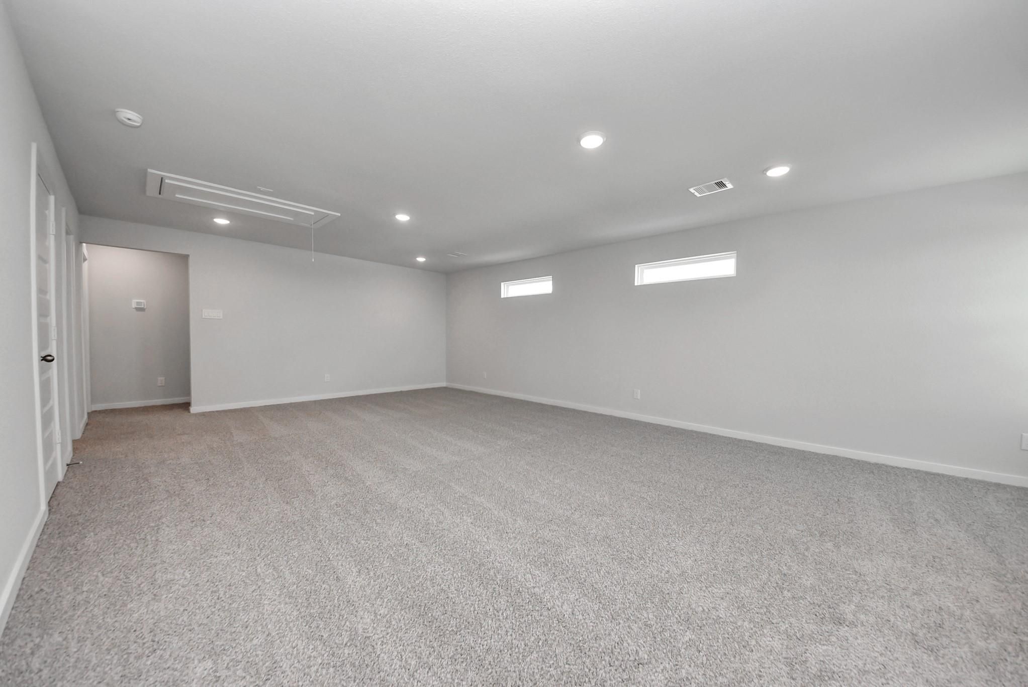 Spacious carpeted game room with recessed lighting and clerestory windows in Davidson Homes The San Marcos E, Emberly, Beasley TX