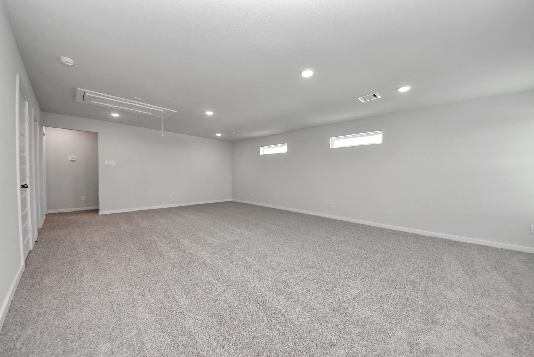 Spacious carpeted game room with recessed lighting and clerestory windows in Davidson Homes The San Marcos E, Emberly, Beasley TX