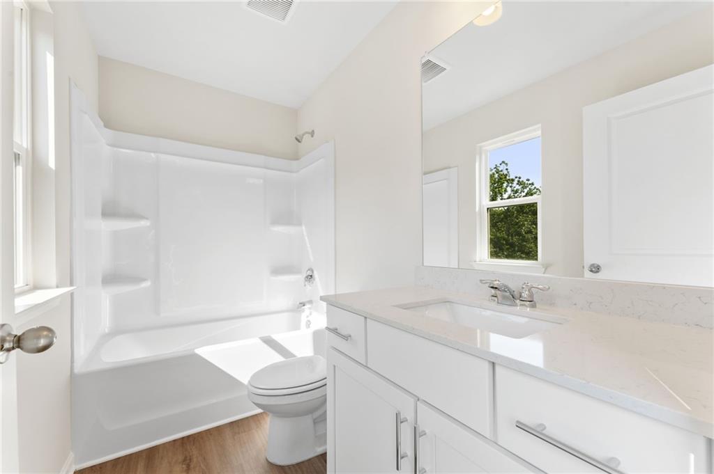 Bright bathroom with white tub, vanity sink, toilet and window in The Willow B 4-bedroom home by Davidson Homes, Riverwood, Dallas, Georgia