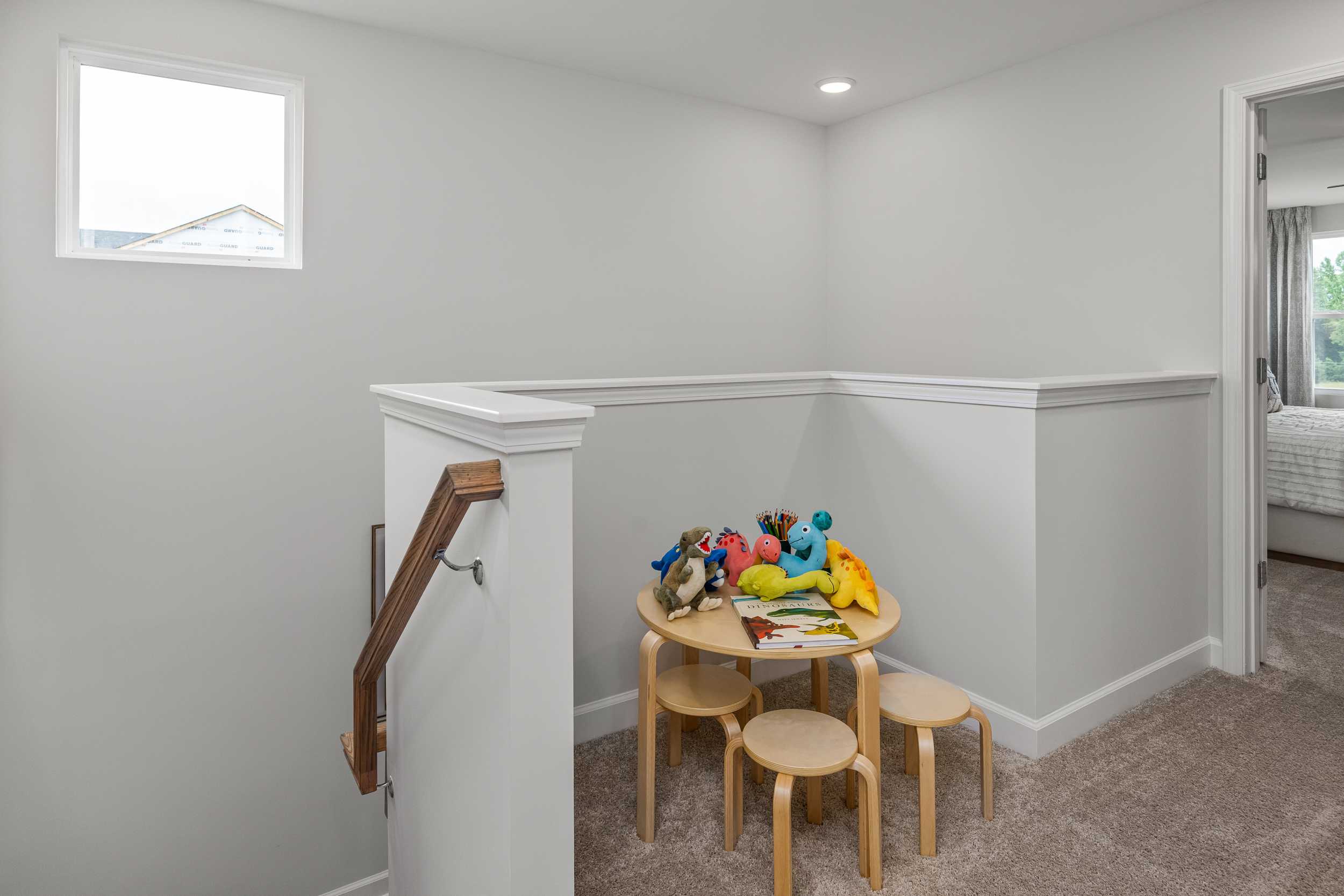 Cozy loft playroom in Springvale, Fuquay-Varina NC with wooden kids' table, colorful stuffed toys, stools, and stair railing