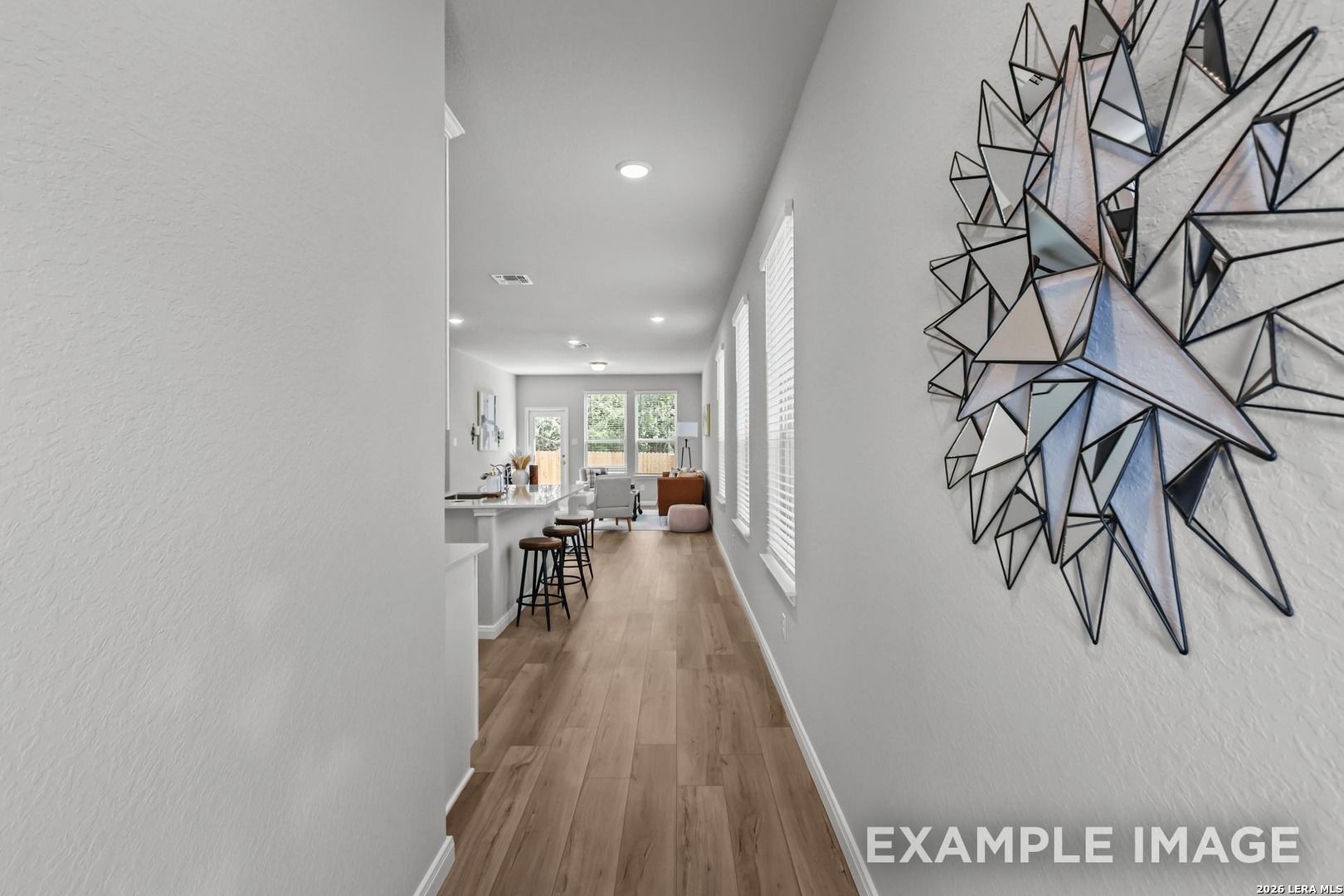 Open-concept hallway leading to living area with geometric wall art in The Gillian A floor plan, Cedar Heights, San Antonio.