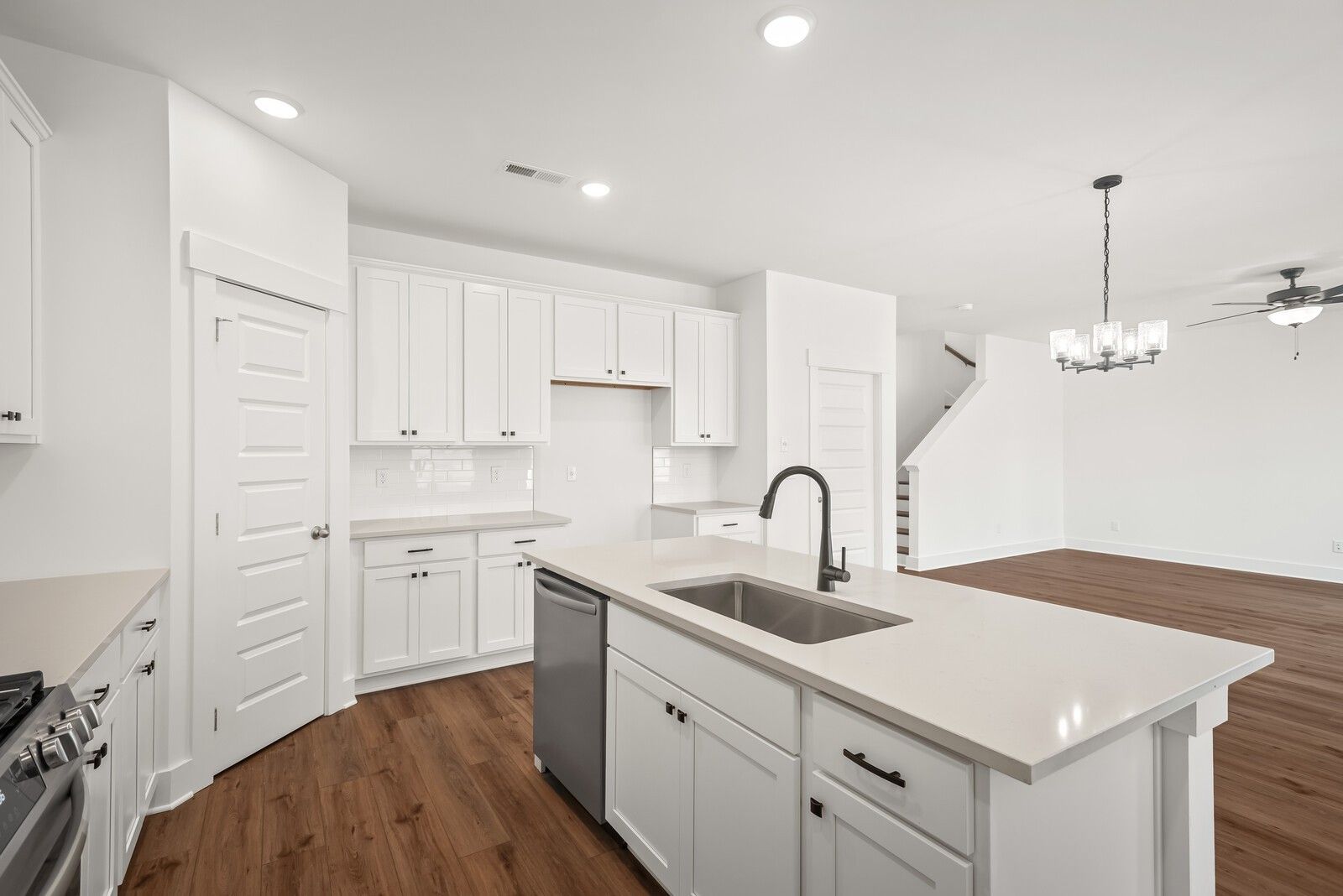 Bright white open-concept kitchen with quartz island, stainless sink, and cabinetry in Davidson Homes The Logan C, Gallatin, TN