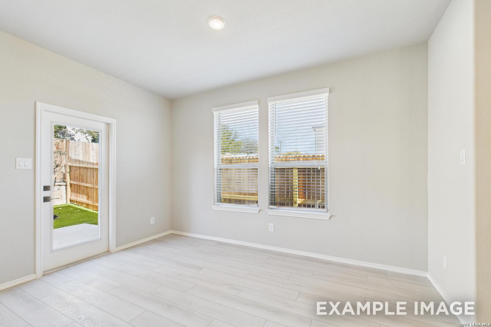 Bright dining area with light wood floors and backyard access in The Charlotte B floor plan at Cedar Heights, San Antonio.