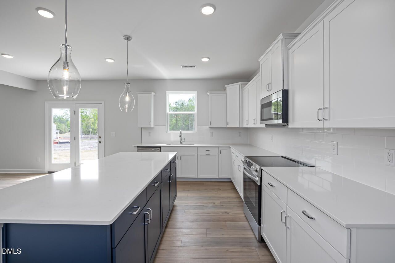 Modern kitchen with white shaker cabinets, navy island, quartz counters, stainless appliances in The Hickory II B, Zebulon, NC
