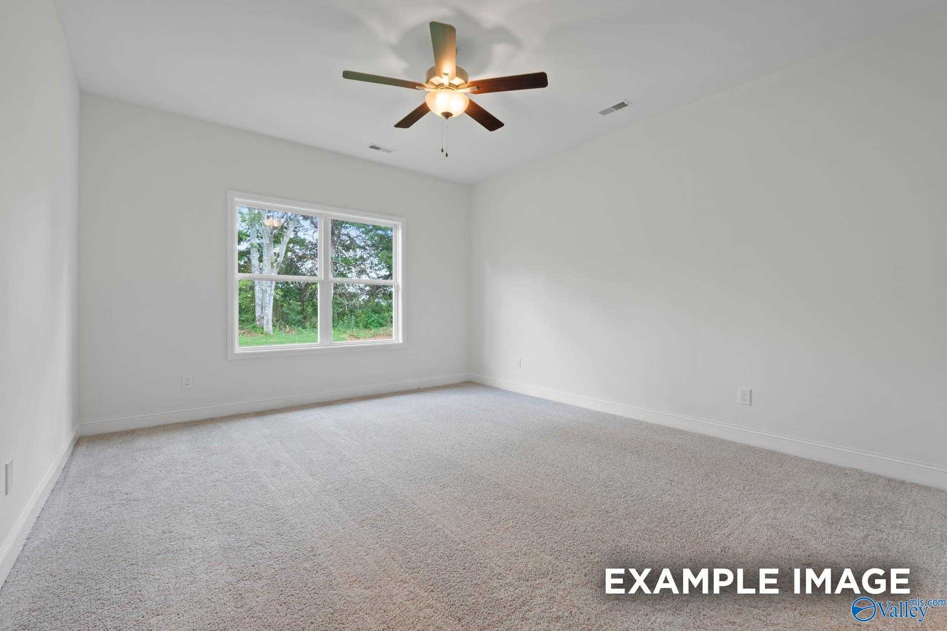 Bright empty bedroom featuring large window, ceiling fan, and carpeted floor in The Daphne D 4-bedroom home, Athens, Alabama