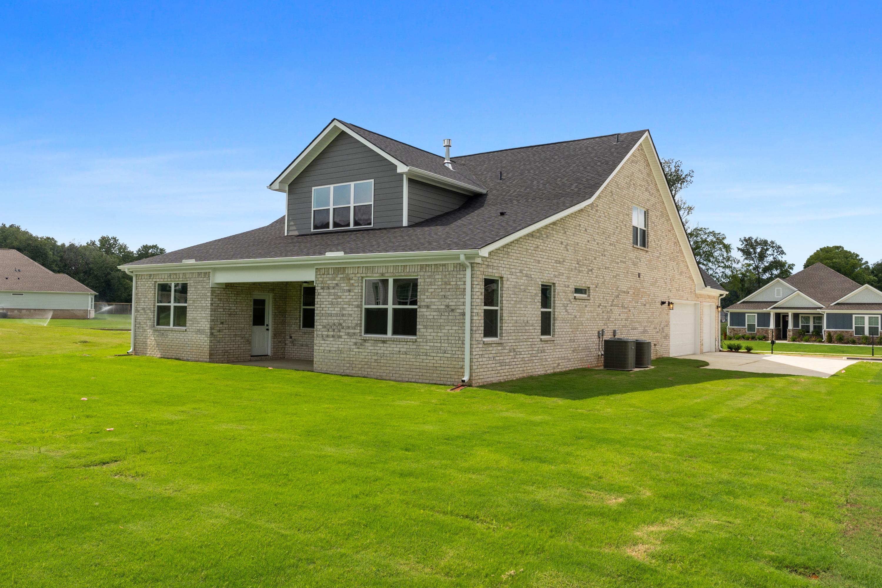 Two-story brick The Oxford home design by Evermore Homes featuring covered porch, 3-car garage, and lush green lawn in Owens Cross Roads
