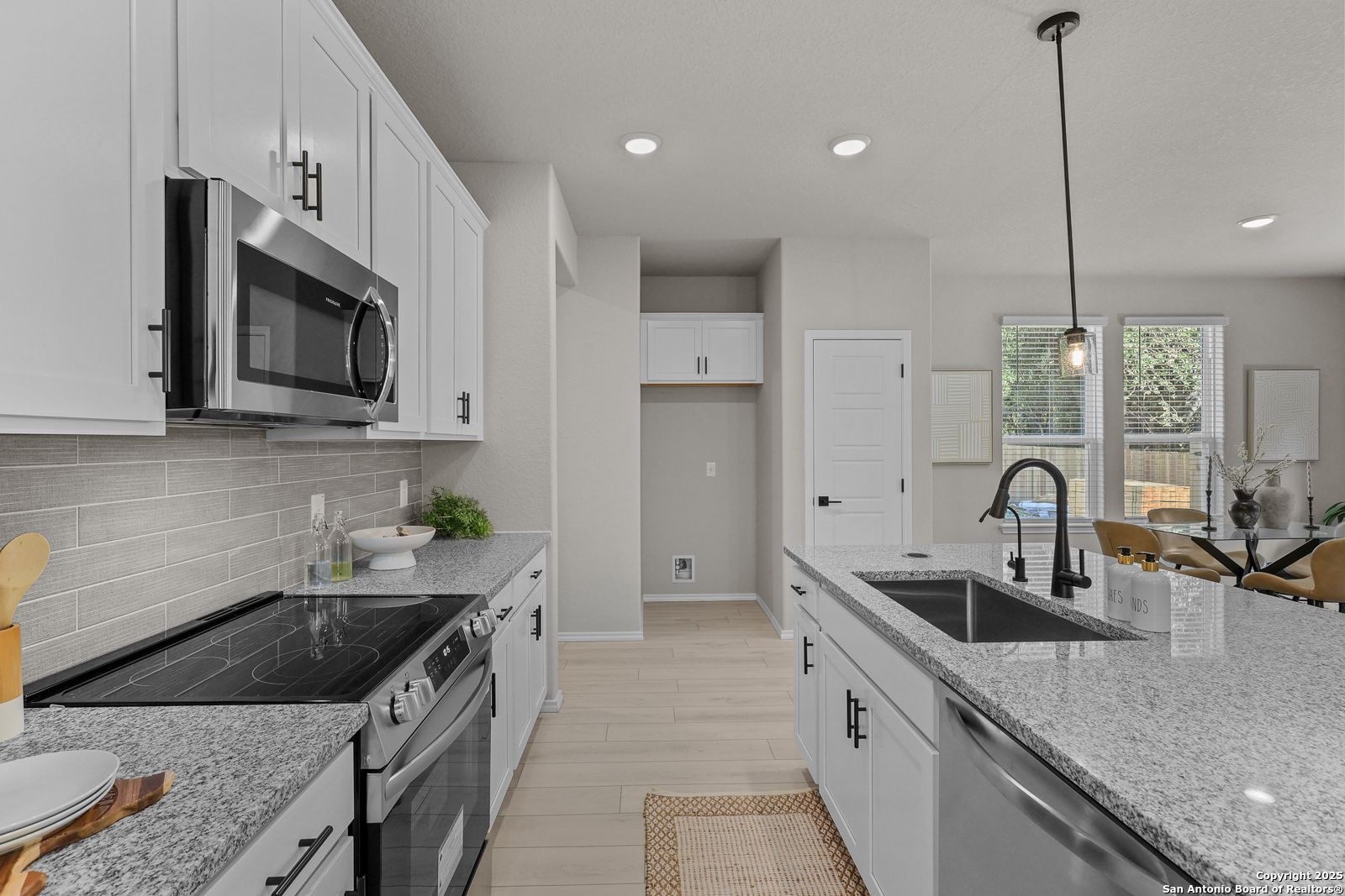 Modern open-concept kitchen with white shaker cabinets, granite countertops, stainless steel appliances in Davidson Homes The Charlotte B, San Antonio