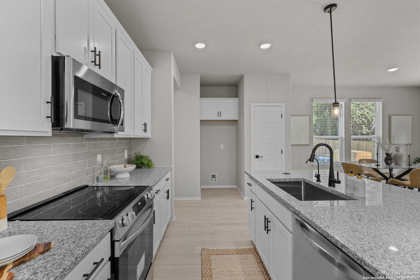 Modern open-concept kitchen with white shaker cabinets, granite countertops, stainless steel appliances in Davidson Homes The Charlotte B, San Antonio