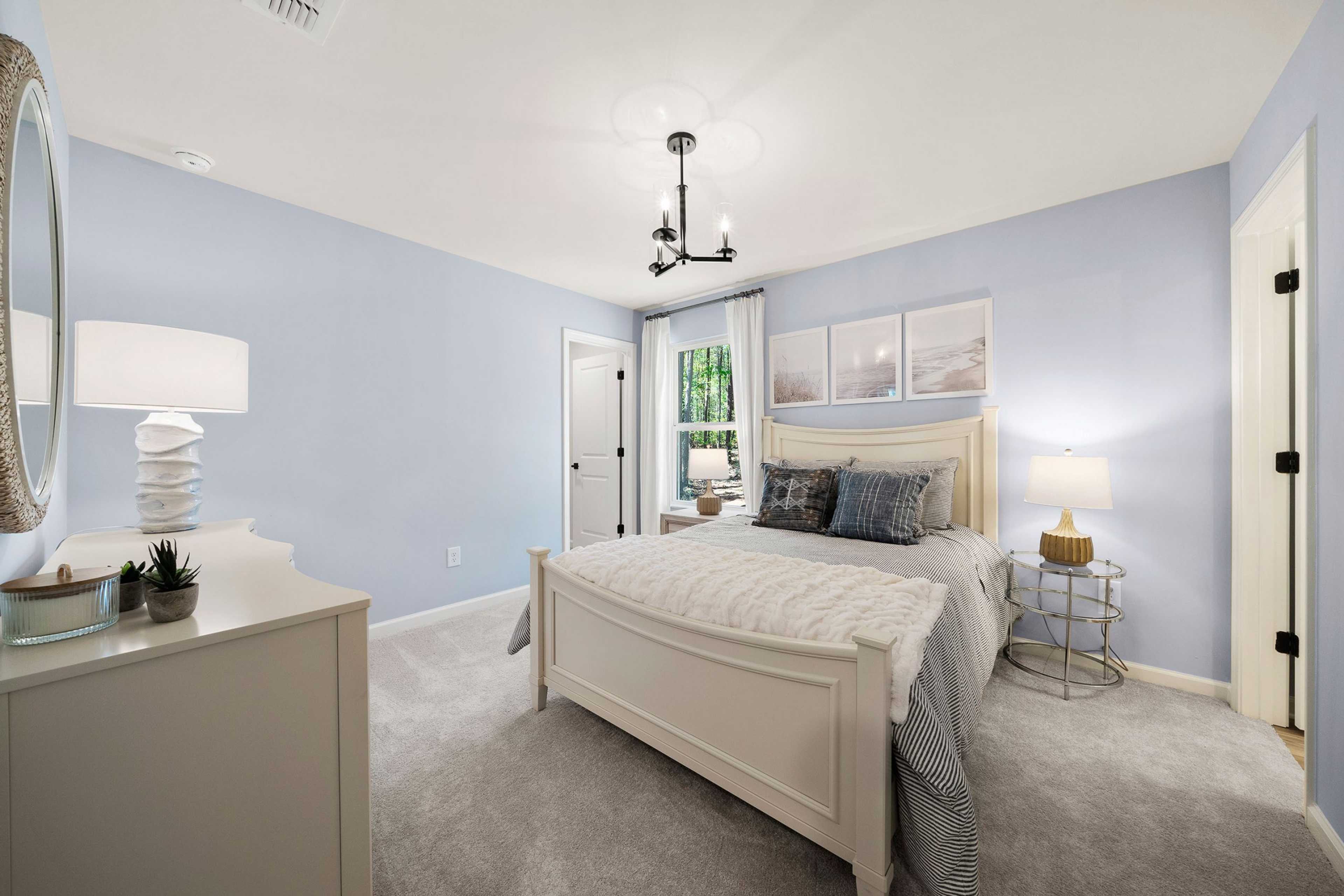 Light blue master bedroom at Riverwood in Dallas, Georgia with white bed, chandelier, lamps, and sheer curtains