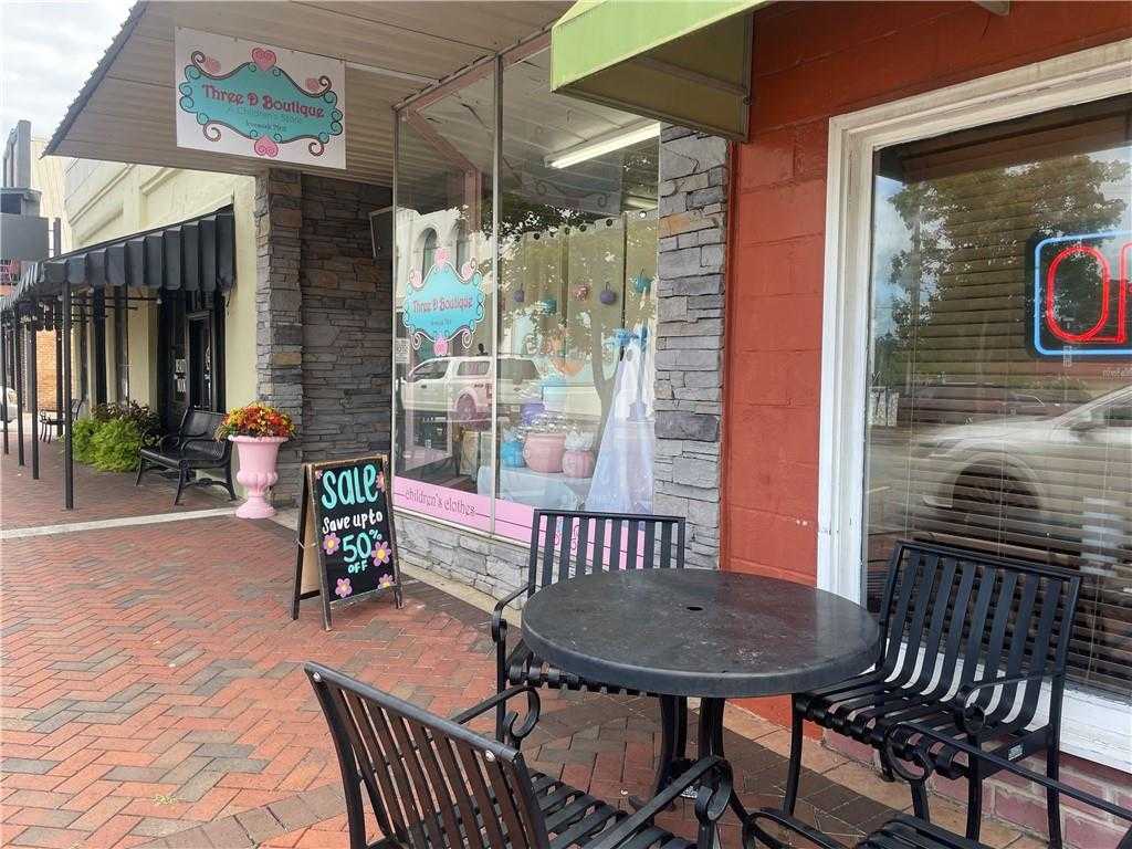 Charming Tea & Tulips boutique storefront with 20% off sale sign, outdoor bistro seating on brick patio amid flowers