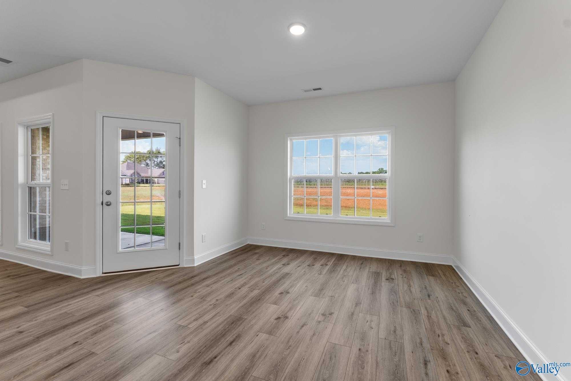 Bright flex room with luxury vinyl plank floors, large windows overlooking fields, and glass door to yard in The Harrison, Meridianville, AL