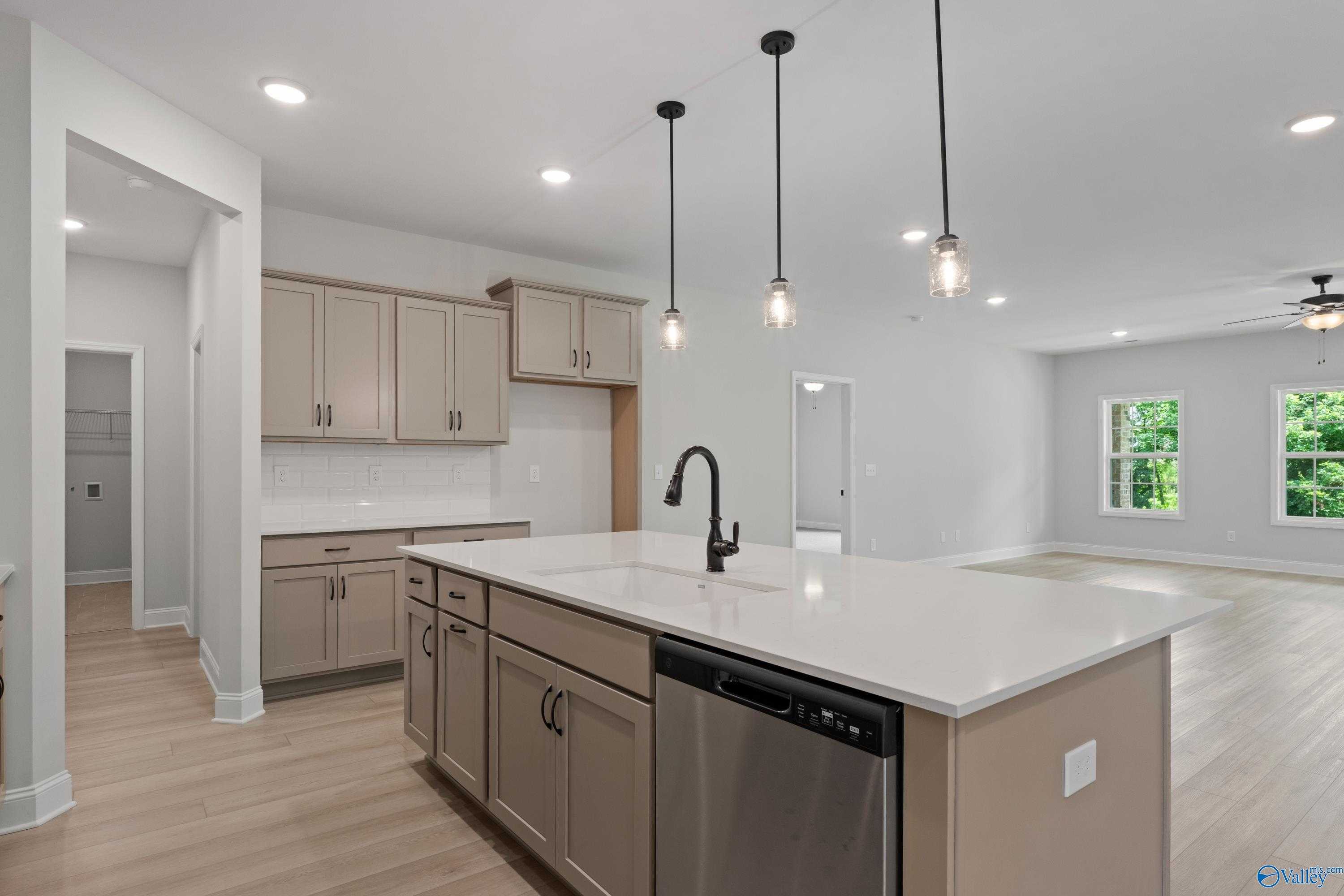Open-concept kitchen with beige cabinets, white quartz island, pendant lights in Davidson Homes The Kirkland, Creekside, Harvest, AL