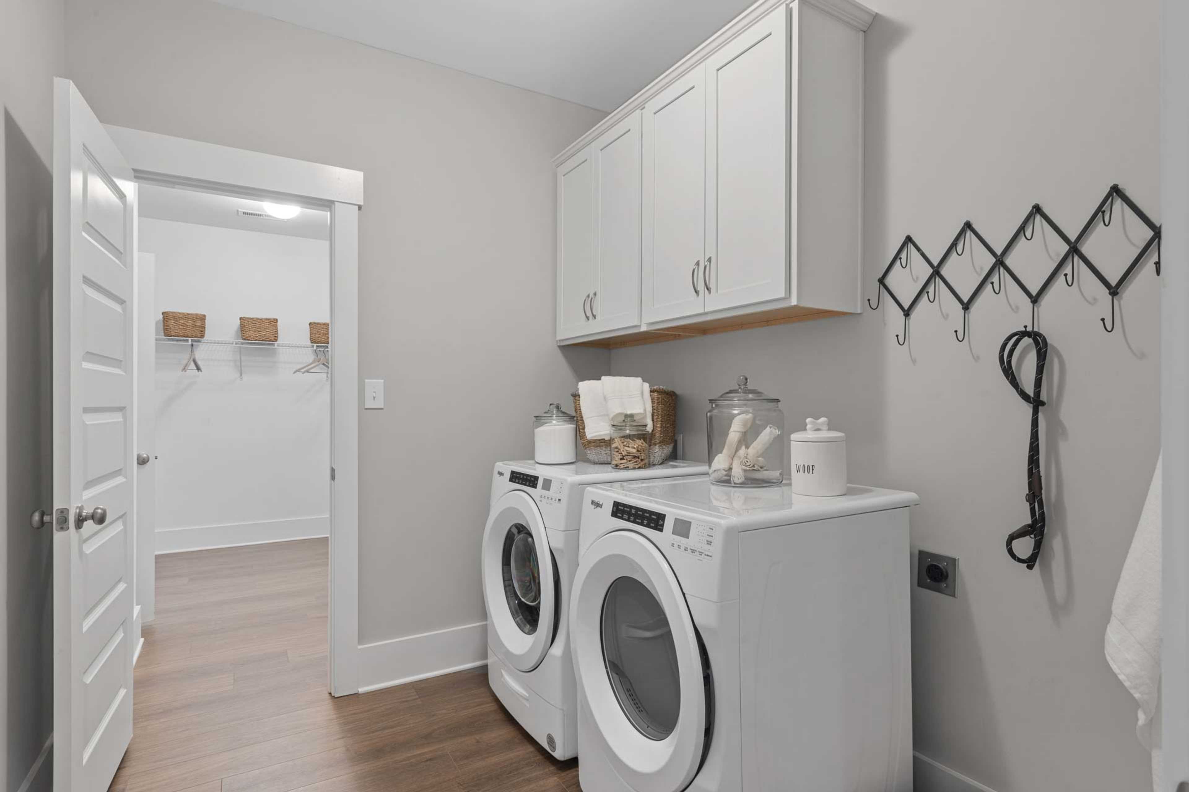 Modern laundry room at Monteagle Cove in Owens Cross Roads AL with white washer dryer, cabinets, hardwood floors