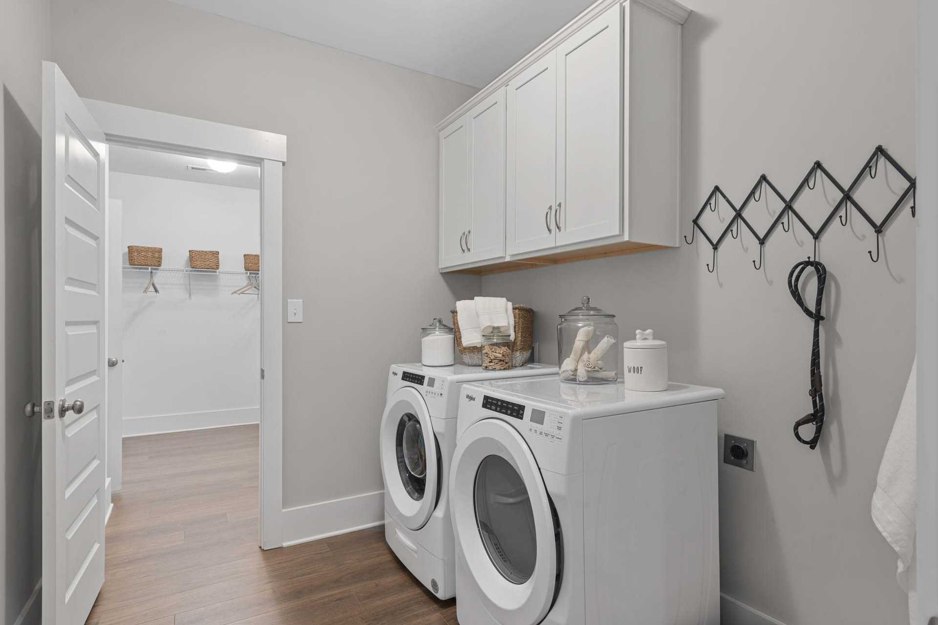 Modern laundry room at Monteagle Cove in Owens Cross Roads AL with white washer dryer, cabinets, hardwood floors