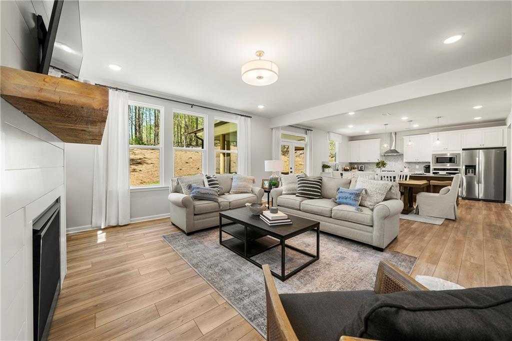 Spacious open-concept living room with shiplap walls, gas fireplace, large windows, and modern kitchen in Davidson Homes The Hickory B, Riverwood, Dallas, GA