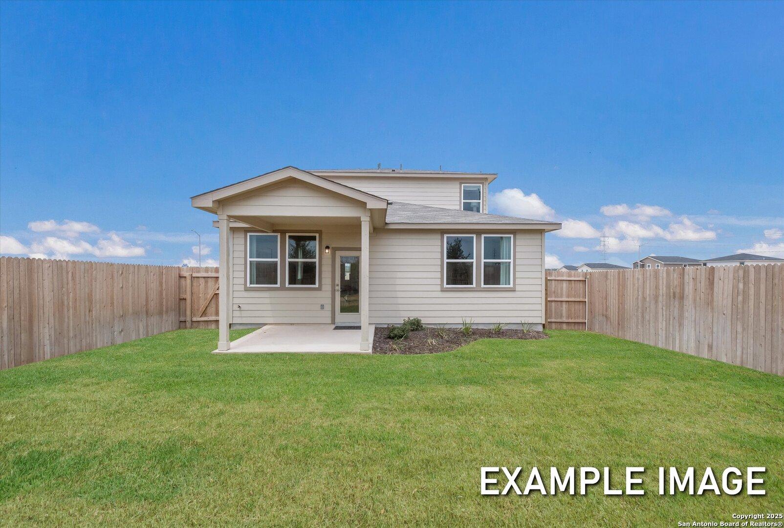 Two-story beige home with covered porch, windows, and fenced grassy yard under blue sky in Agave, San Antonio, Texas