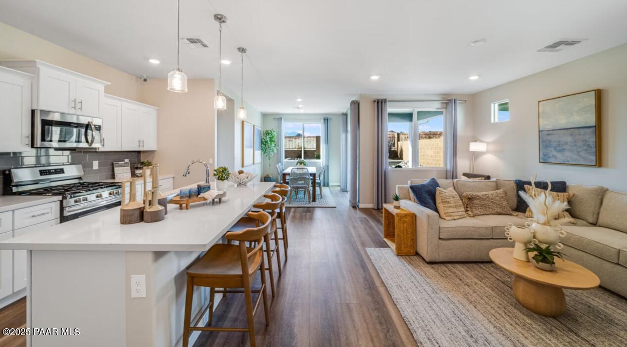 Open-concept kitchen with white quartz island, stainless appliances, and adjacent living-dining area in Davidson Homes The Newport C, Prescott, AZ