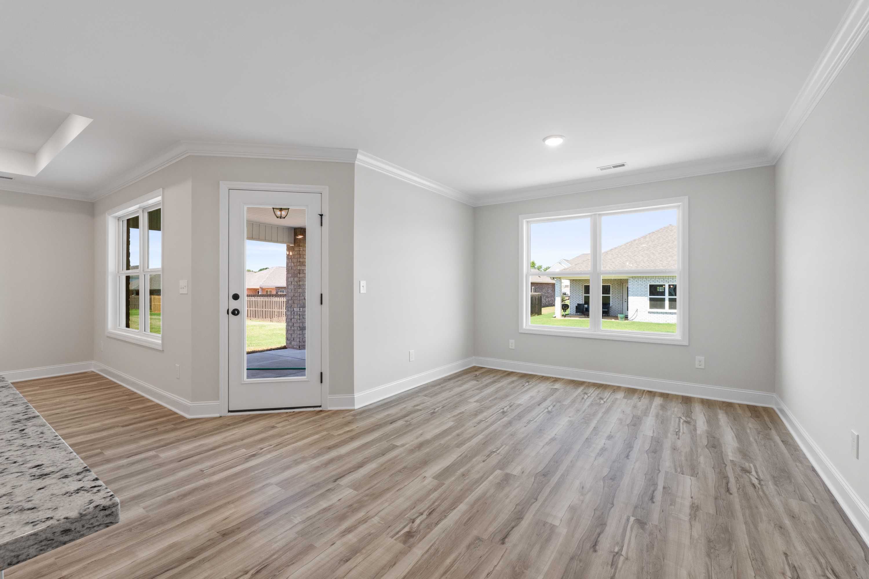 Spacious open-concept living area in The Everett C with light gray walls, hardwood floors, French doors to backyard patio