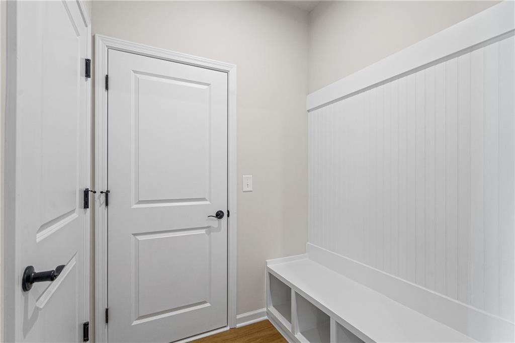 White shiplap mudroom with built-in bench, storage shelves, and double doors in Davidson Homes The Edison B, Loganville, GA